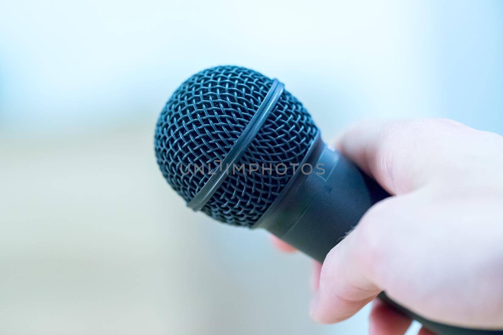 Close up picture of a hand which is holding a black microphone.