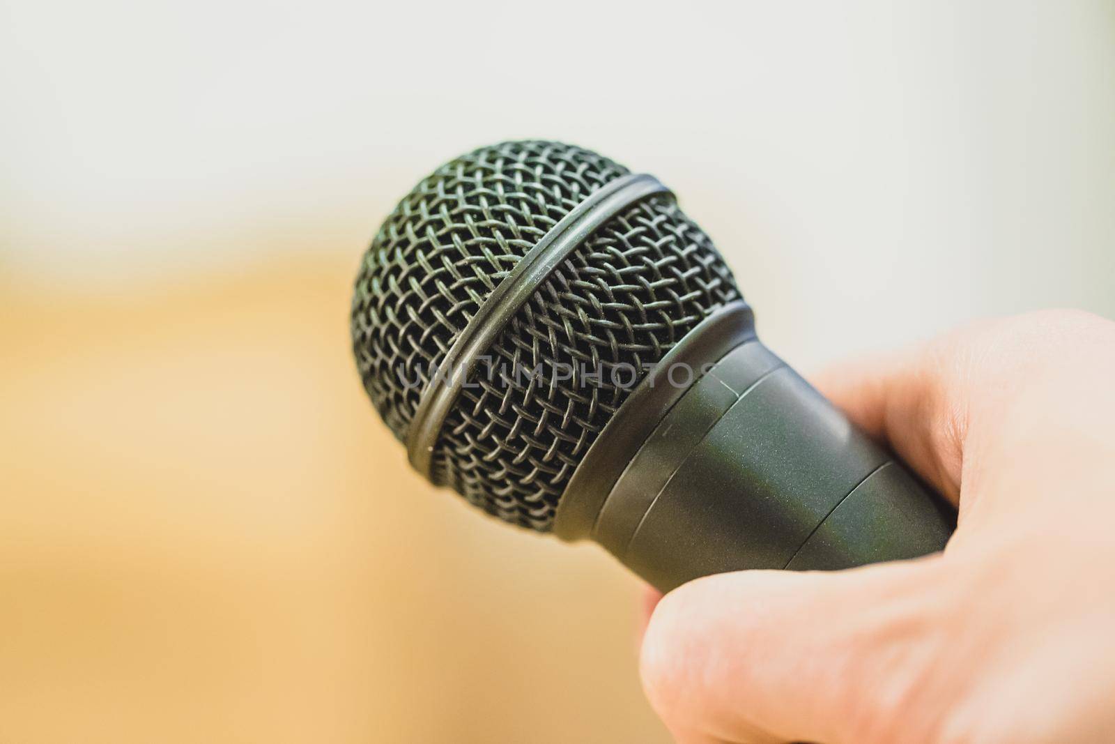 Close up picture of a hand which is holding a black microphone.