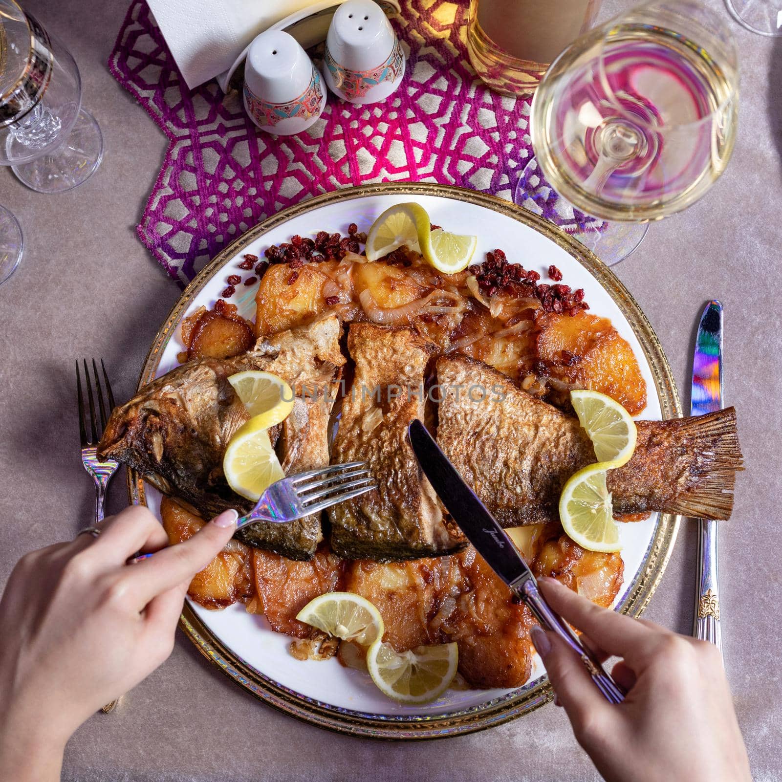 Woman eating a grilled whole fish with a lemon top view