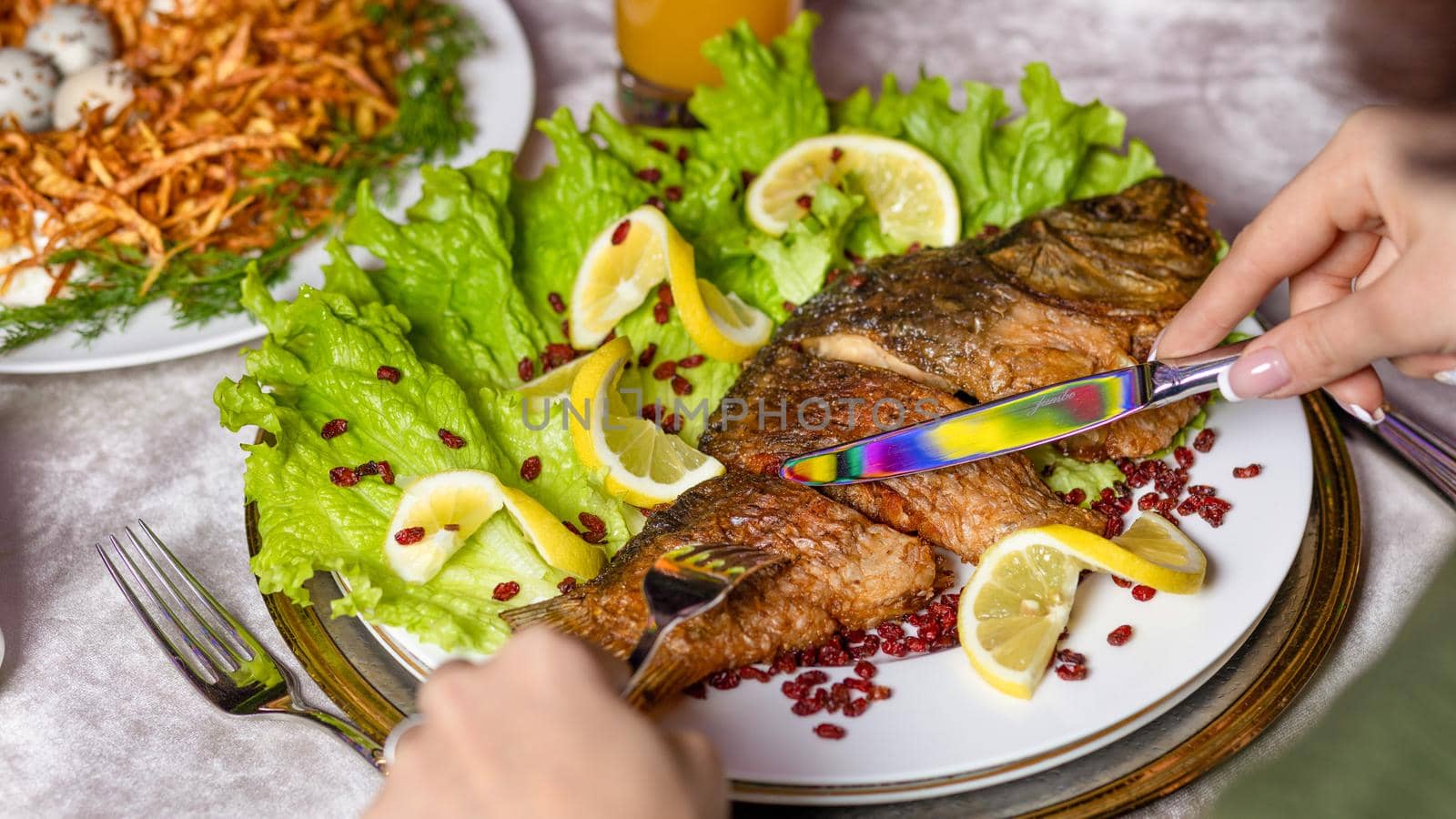 Woman eating a grilled whole fish with a lemon