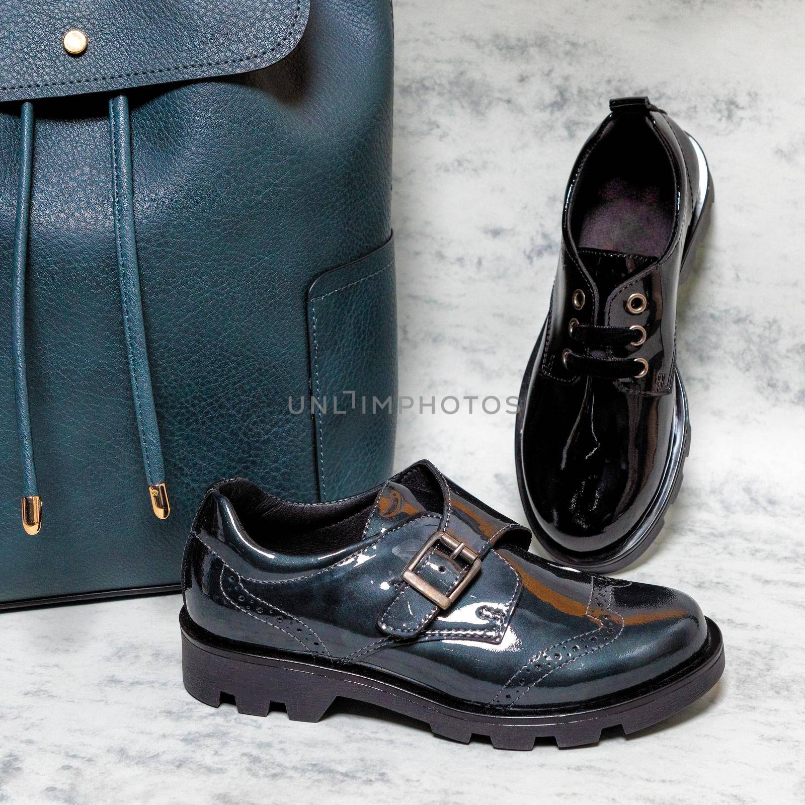 Black shiny boy male shoes with a blue backpack isolated