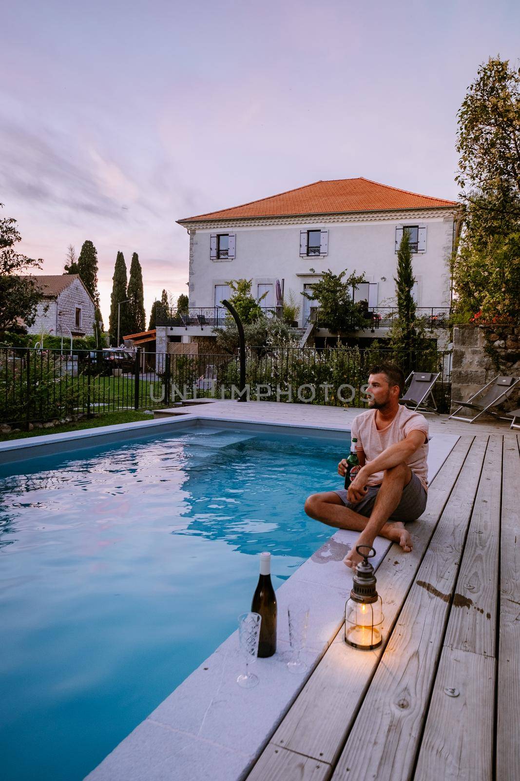 French vacation home with wooden deck and swimming pool in the Ardeche France Europe. guy relaxing by the pool with wooden deck during luxury vacation at an holiday home in South of France