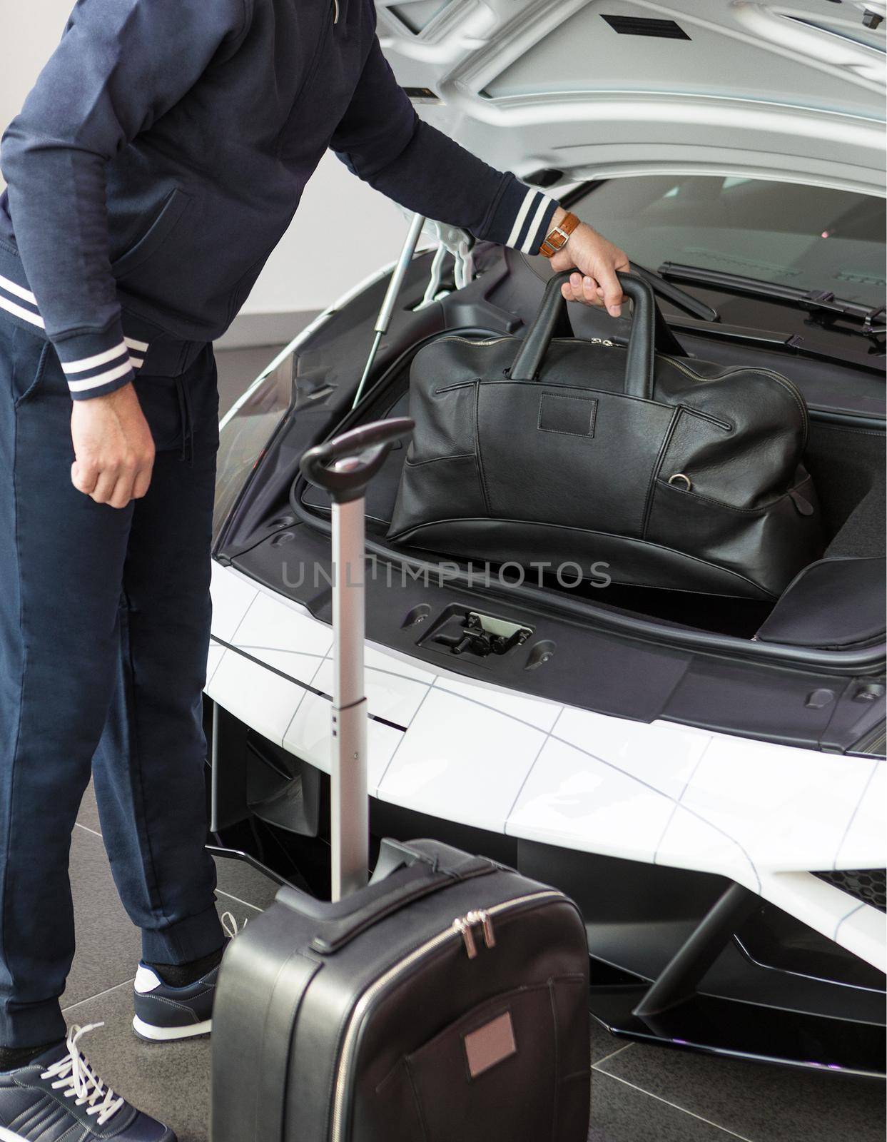 Man putting bag, baggage to the sports car front luggage