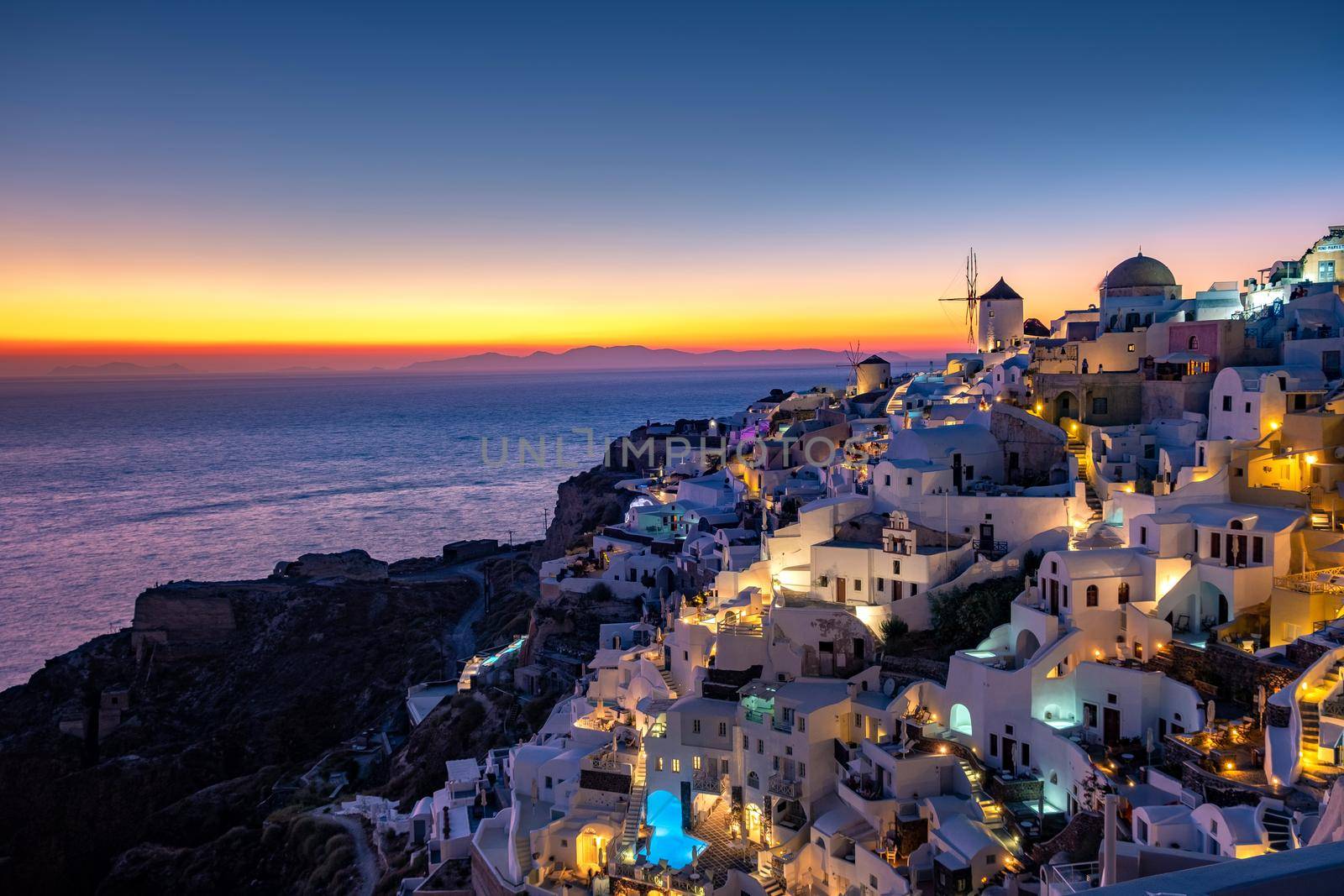 Sunset at the Island Of Santorini Greece, beautiful whitewashed village Oia with church and windmill during sunset by fokkebok