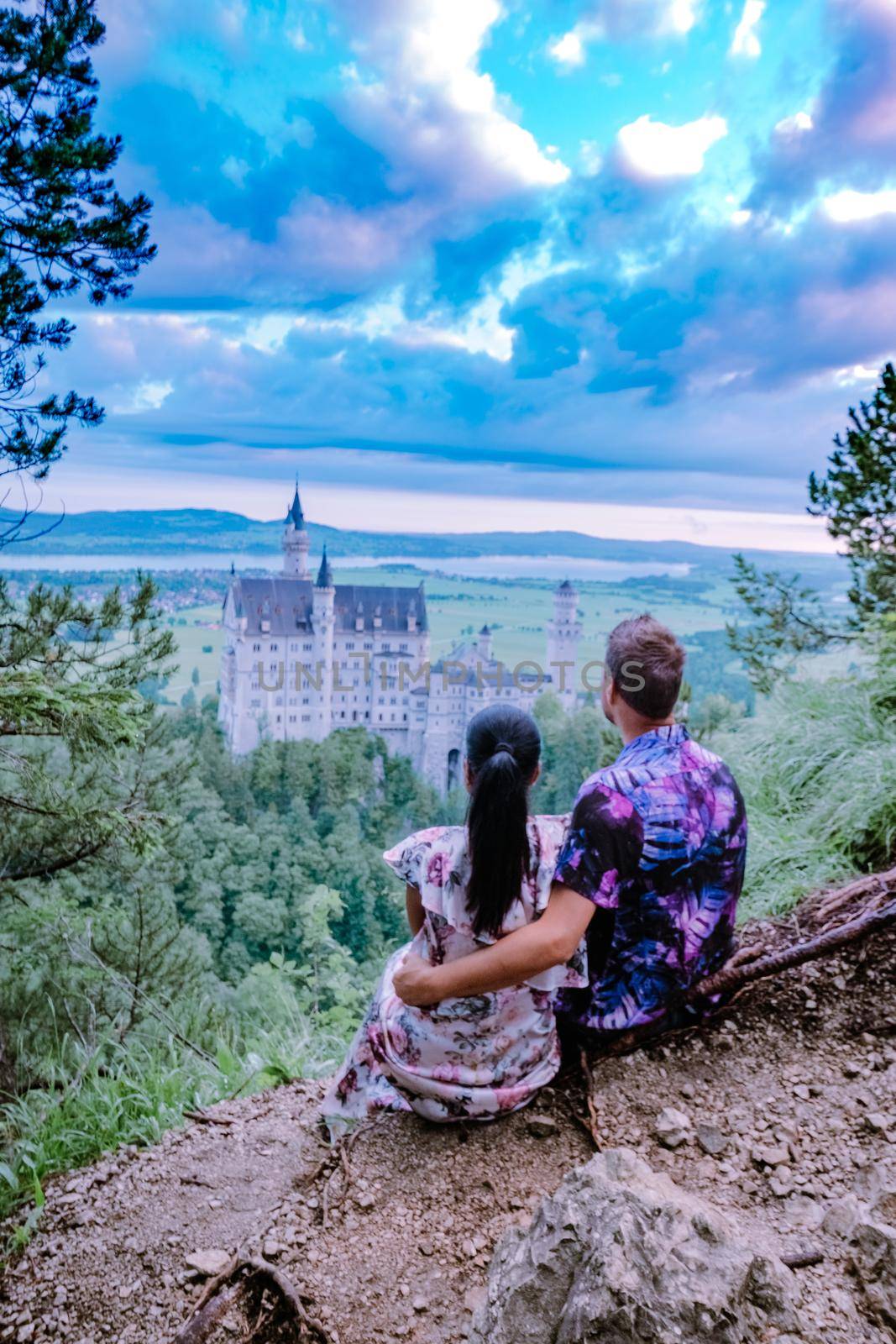 couple men and woman visit Neuschwanstein Castle. Beautiful view of world-famous Neuschwanstein Castle, the nineteenth-century Romanesque Revival palace built for King Ludwig II on a rugged cliff near Fussen, southwest Bavaria, Germany by fokkebok