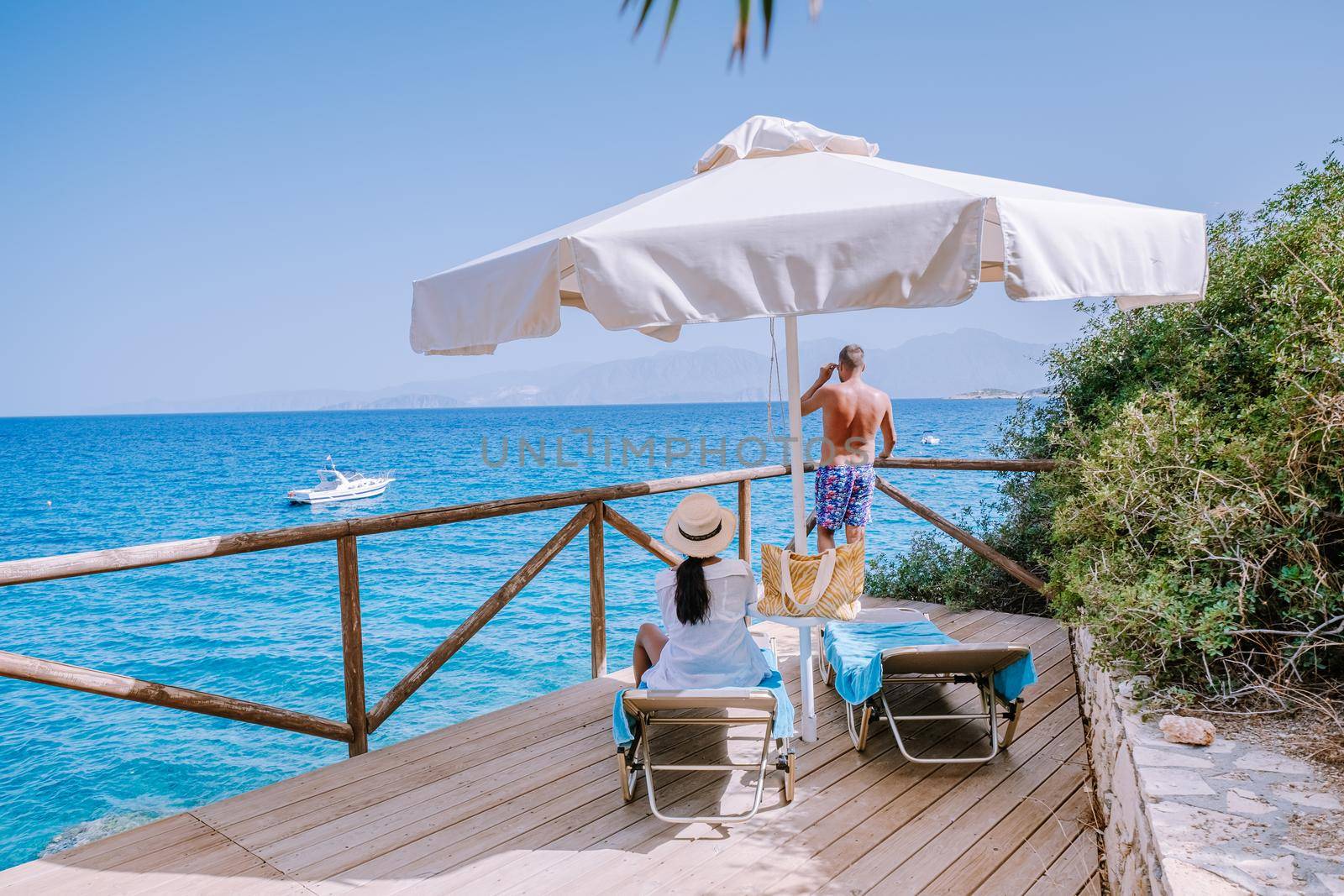 couple by the ocean on sunbed by the ocean on the beach of Crete Greece by fokkebok