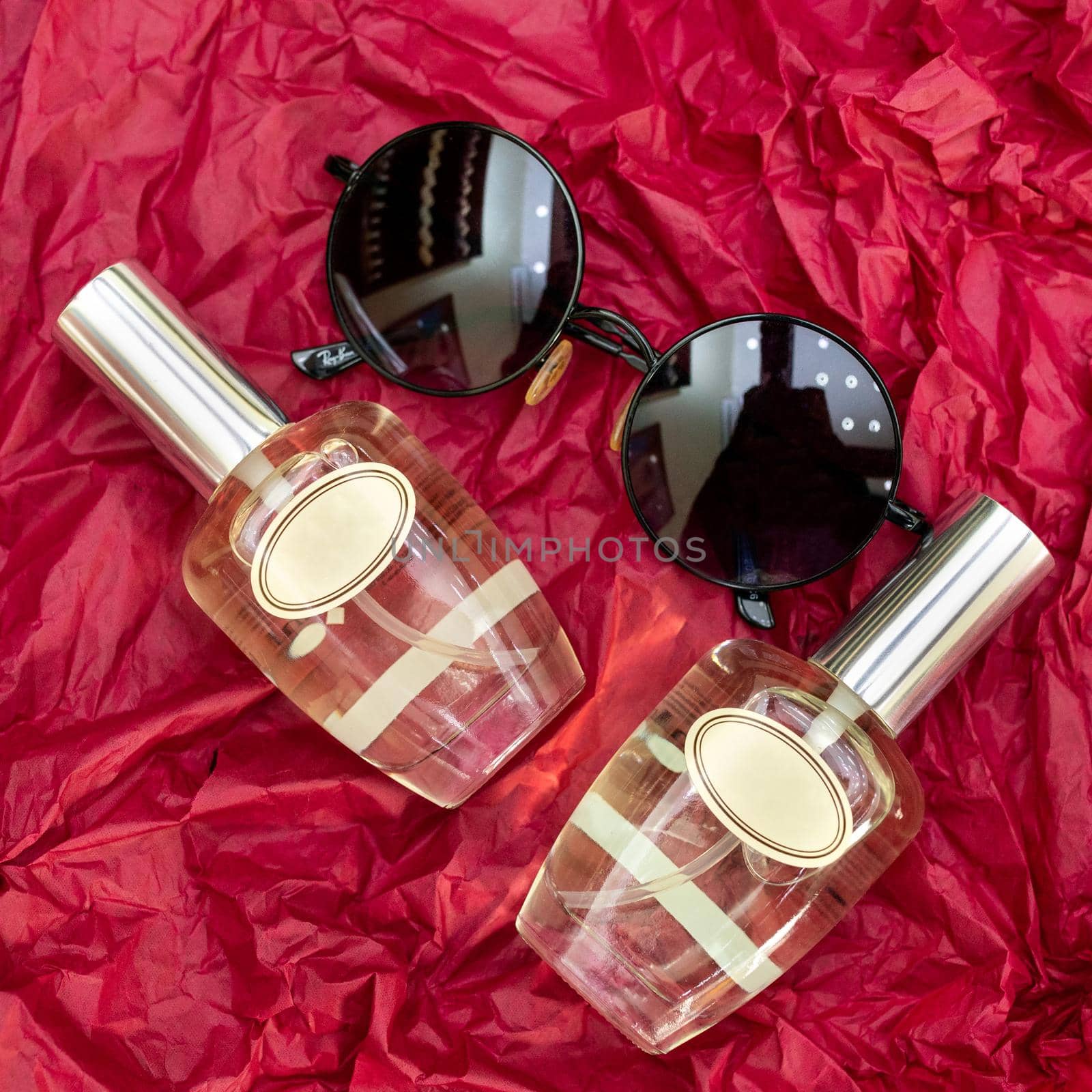 Perfume flacon with sunglass on the red cellophane