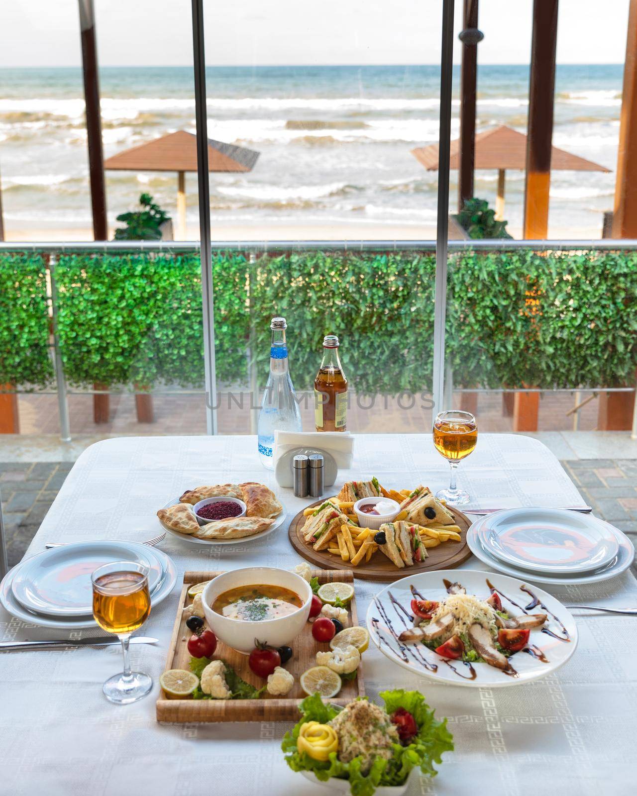 Club sandwich with french fries and soup, salad on the table with sea view