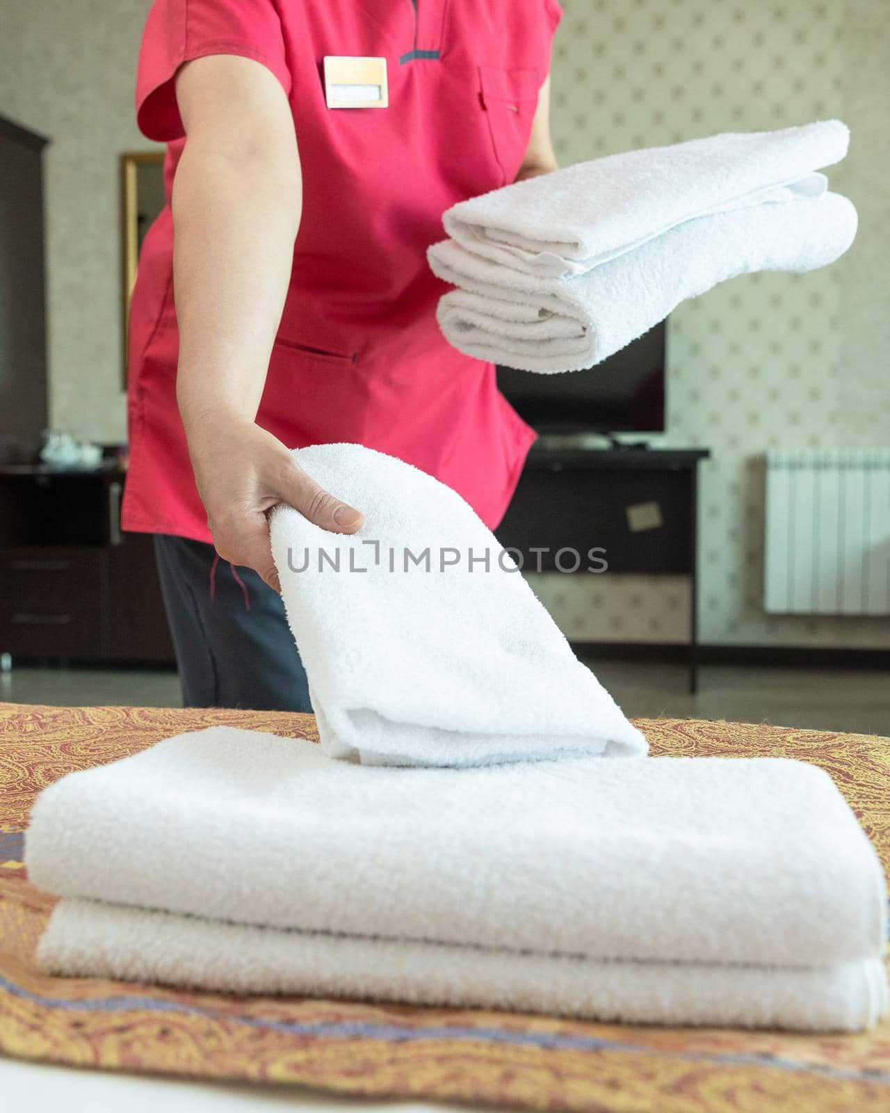 Hotel room service, woman puts a towel on the bed