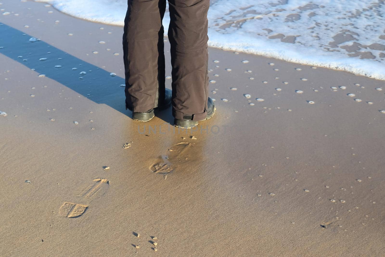 Human feet in black shoes at a baltic sea beach in northern Germany