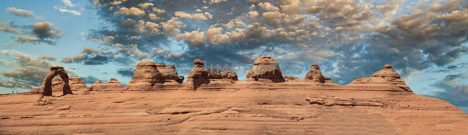 Delicate Arch panoramic view, Arches National Park. High resolution image of rock formations against blue sky.