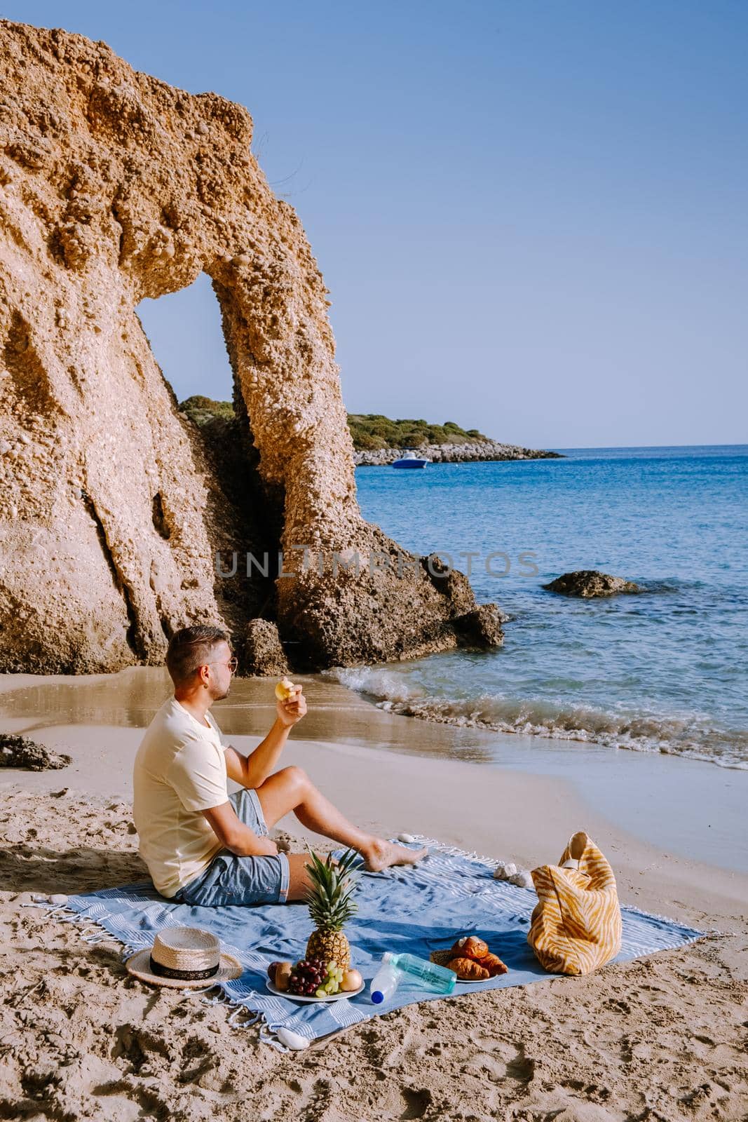 Tropical beach of Voulisma beach, Istron, Crete, Greece ,Most beautiful beaches of Crete island -Istron bay near Agios Nikolaos , young guy mid age on vacation Crete at the beach