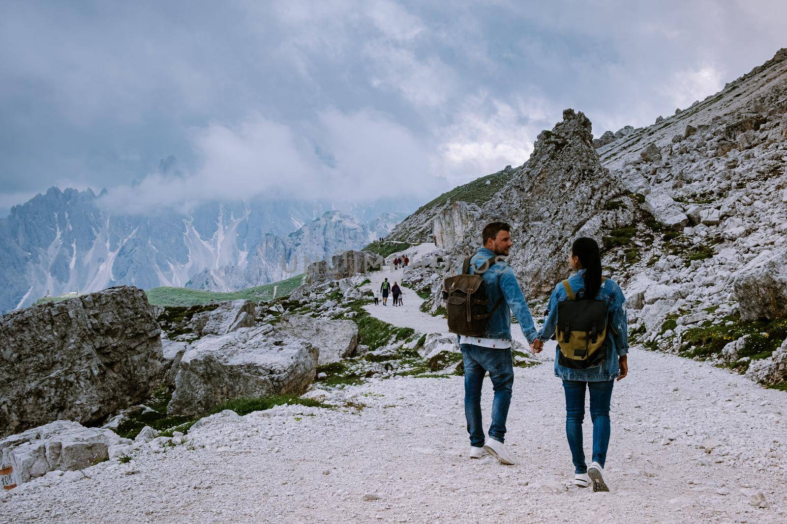 couple hiking in the italian dolomites during foggy weather with clouds, Stunning view to Tre Cime peaks in Dolomites, Italy. Europe