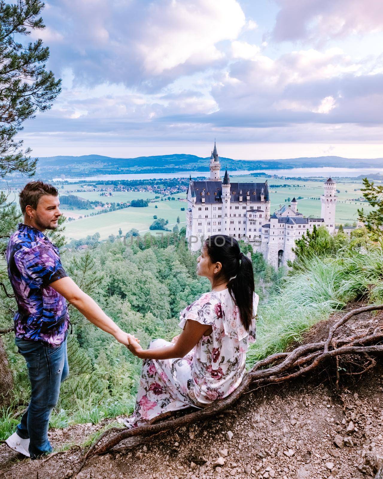 couple men and woman visit Neuschwanstein Castle, Beautiful view of world-famous Neuschwanstein Castle, the nineteenth-century Romanesque Revival palace built for King Ludwig II on a rugged cliff near Fussen, southwest Bavaria, Germany. Europe