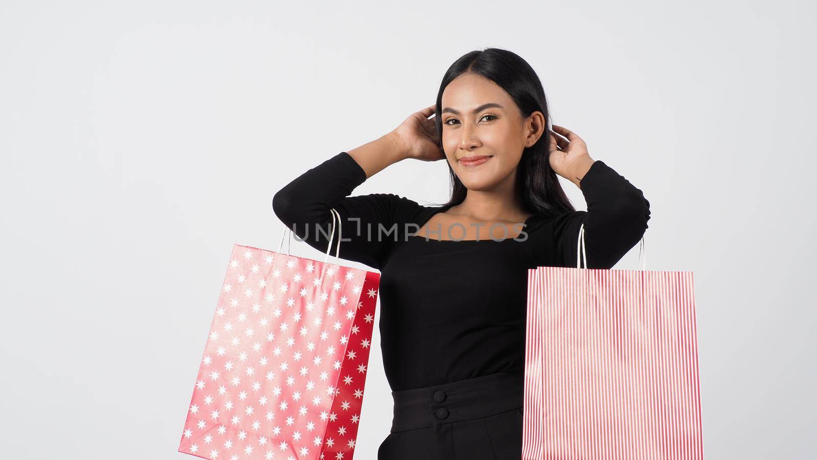 Sexy woman shopping. Portrait of excited beautiful girl wearing black holding red shopping bags isolated over white background. Cheerful happy lady enjoy carrying goods bags. half body.