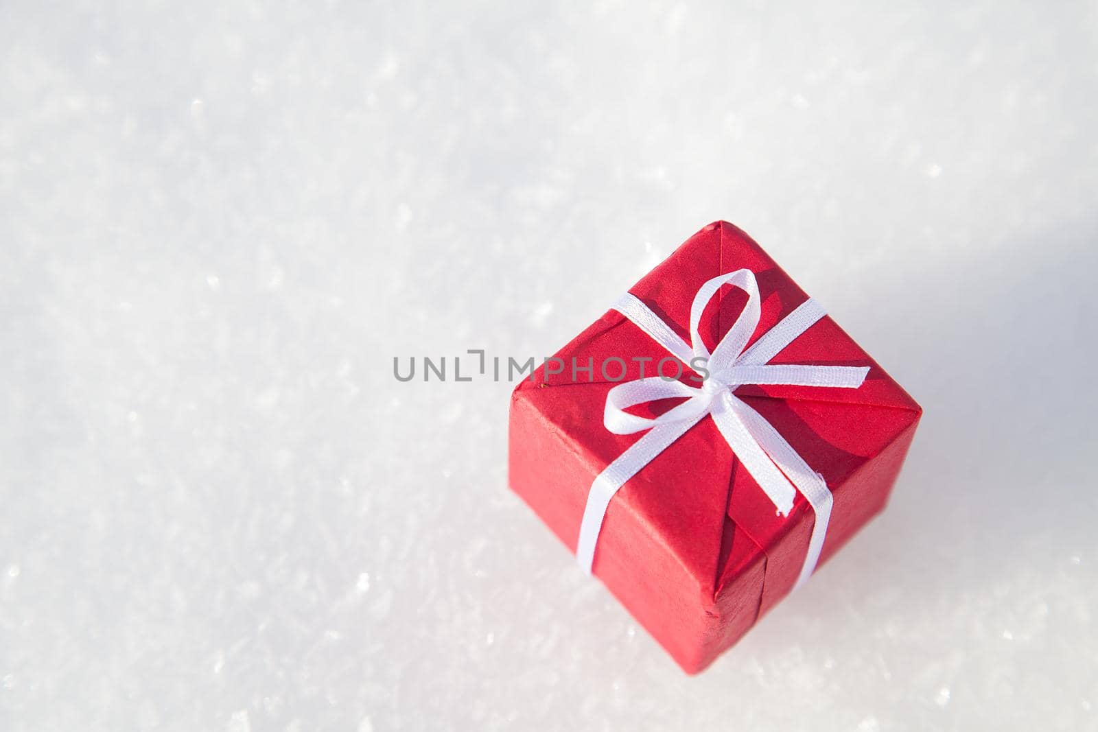 Small Christmas gift box on white snow background with copy space
