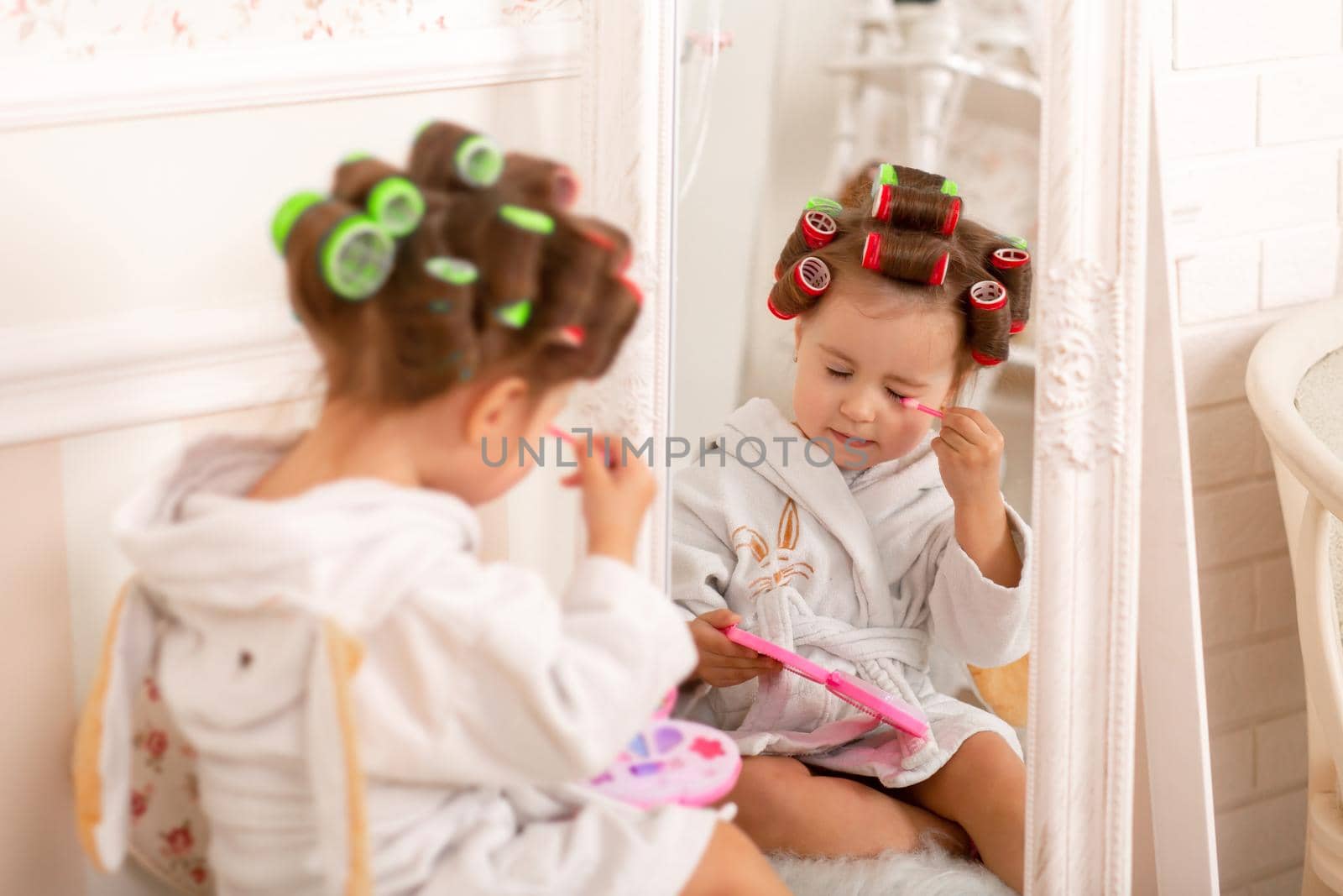 Adorable little girl learns to use baby cosmetics. Beauty day.