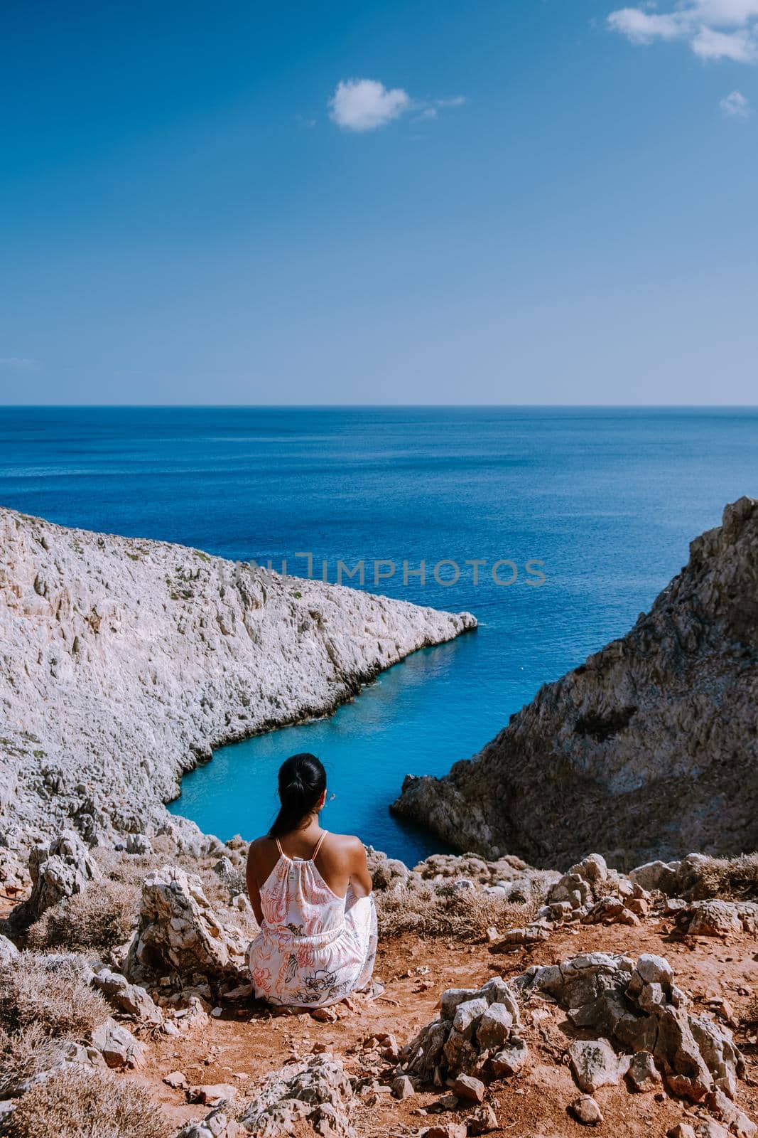 Crete Greece Seitan Limania beach with huge cliff by the blue ocean of the Island of Crete in Greece, Seitan limania beach on Crete, Greece. Europe young woman mid age asian looking out over ocean during vacation