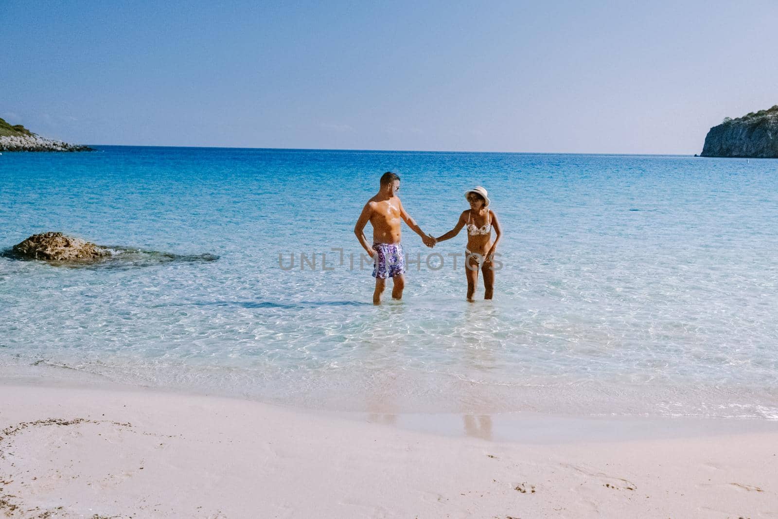 Tropical beach of Voulisma beach, Istron, Crete, Greece ,Most beautiful beaches of Crete island -Istron bay near Agios Nikolaos young couple mid age on vacation in Greece Crete