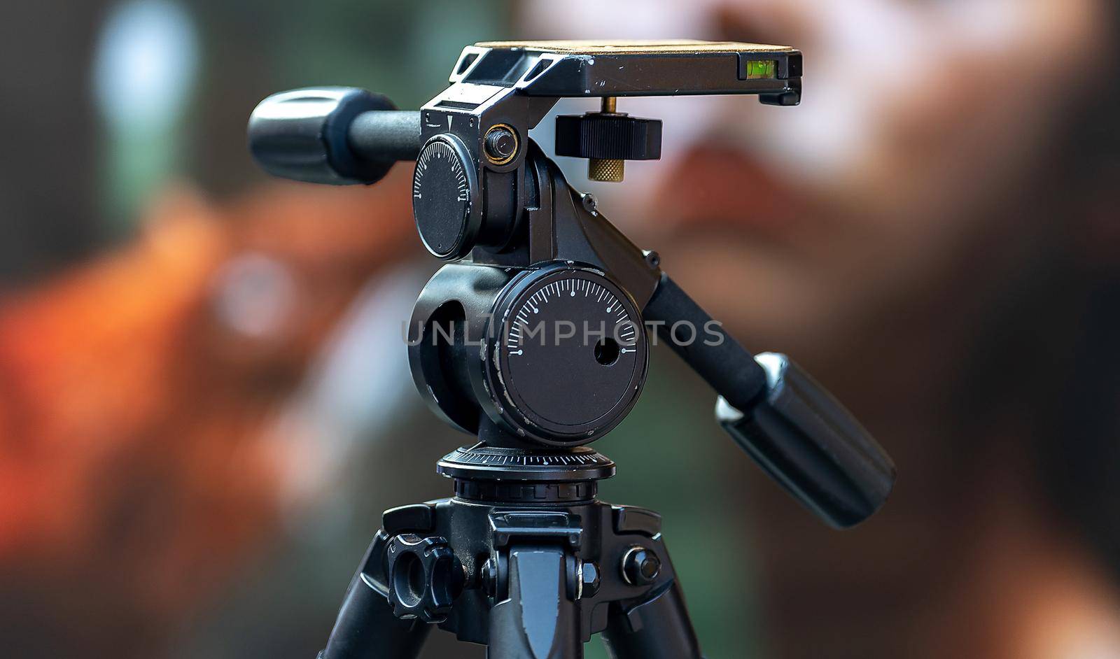 Large black professional tripod with swivel head on a busy street