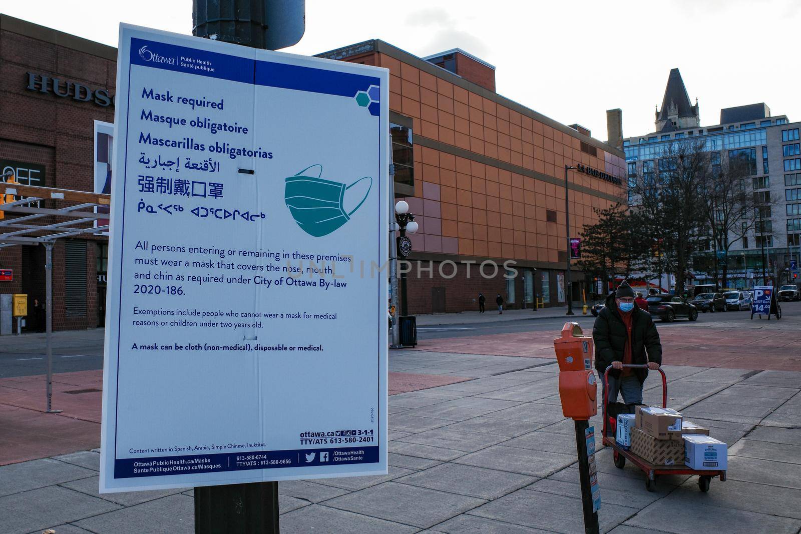 Ottawa, Ontario, Canada - November 18, 2020: A multilingual 'mask required' sign posted by Ottawa Public Health informs pedestrians of a COVID-19 prevention by-law in several languages.