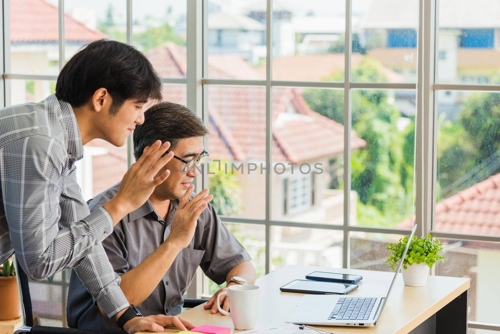 senior and young business man working online on a modern laptop computer by Sorapop