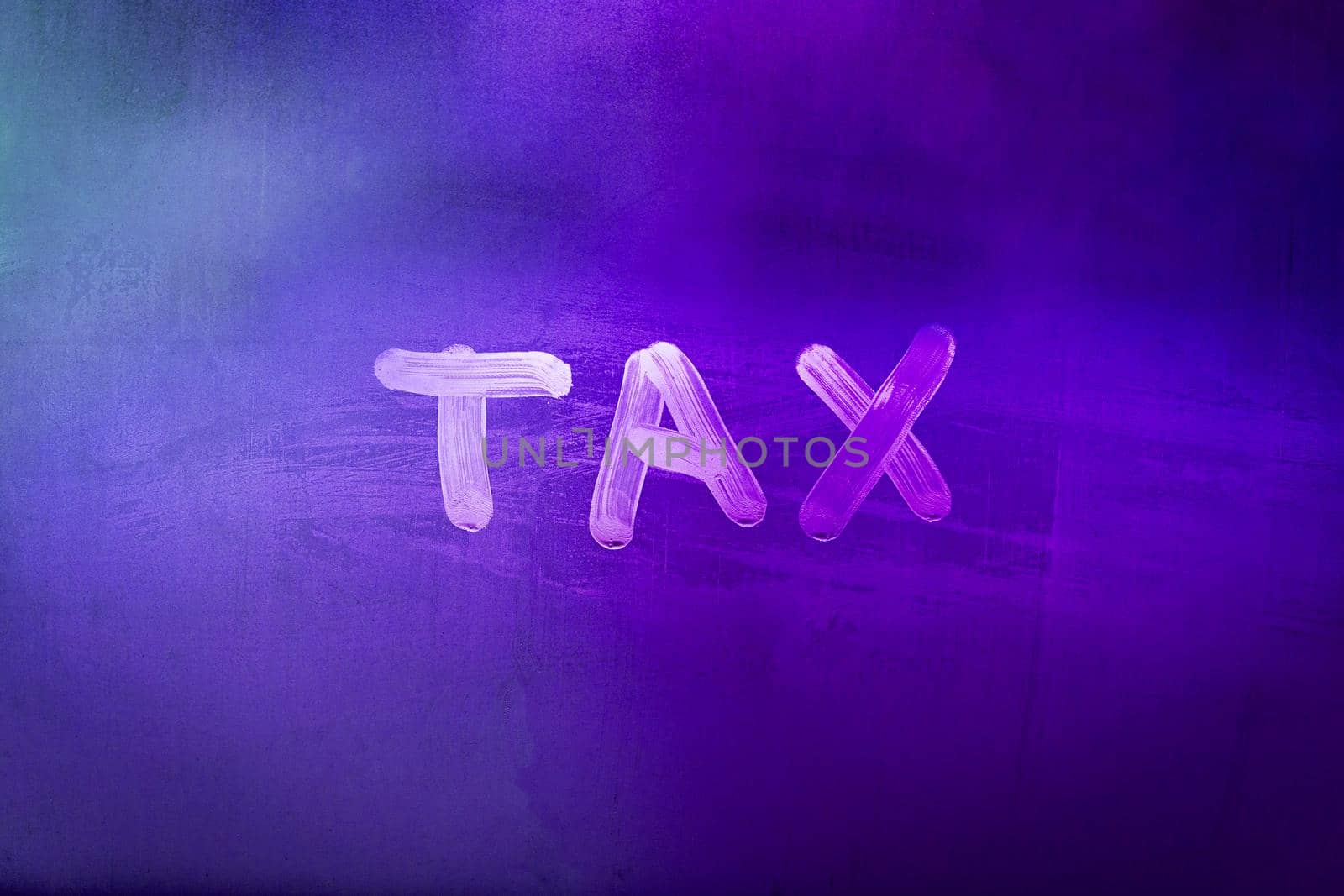 word tax hadwritten on night wet window glass surface with purple color in blurry background