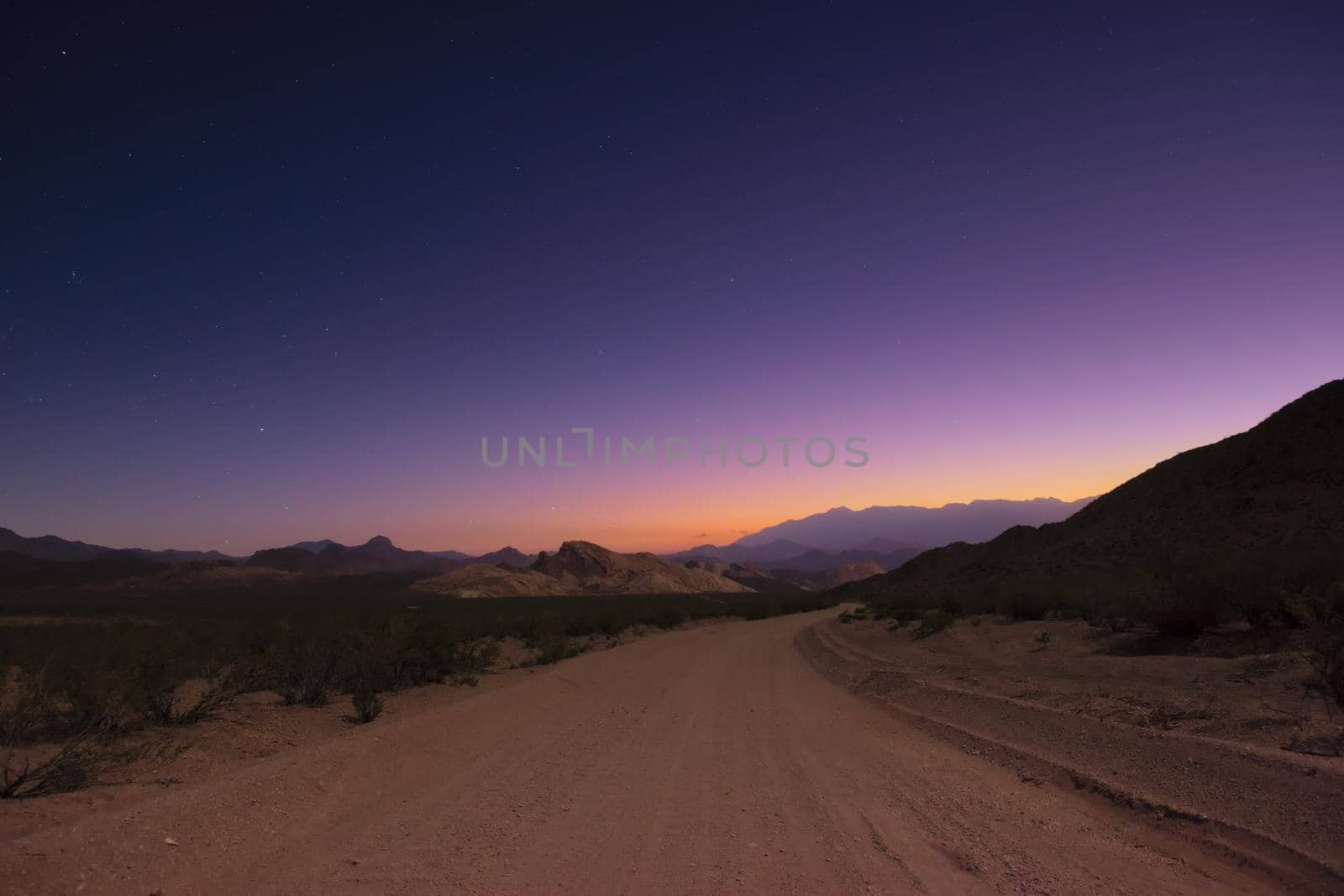 Dirt road into the unknown under a starry twilight sky.