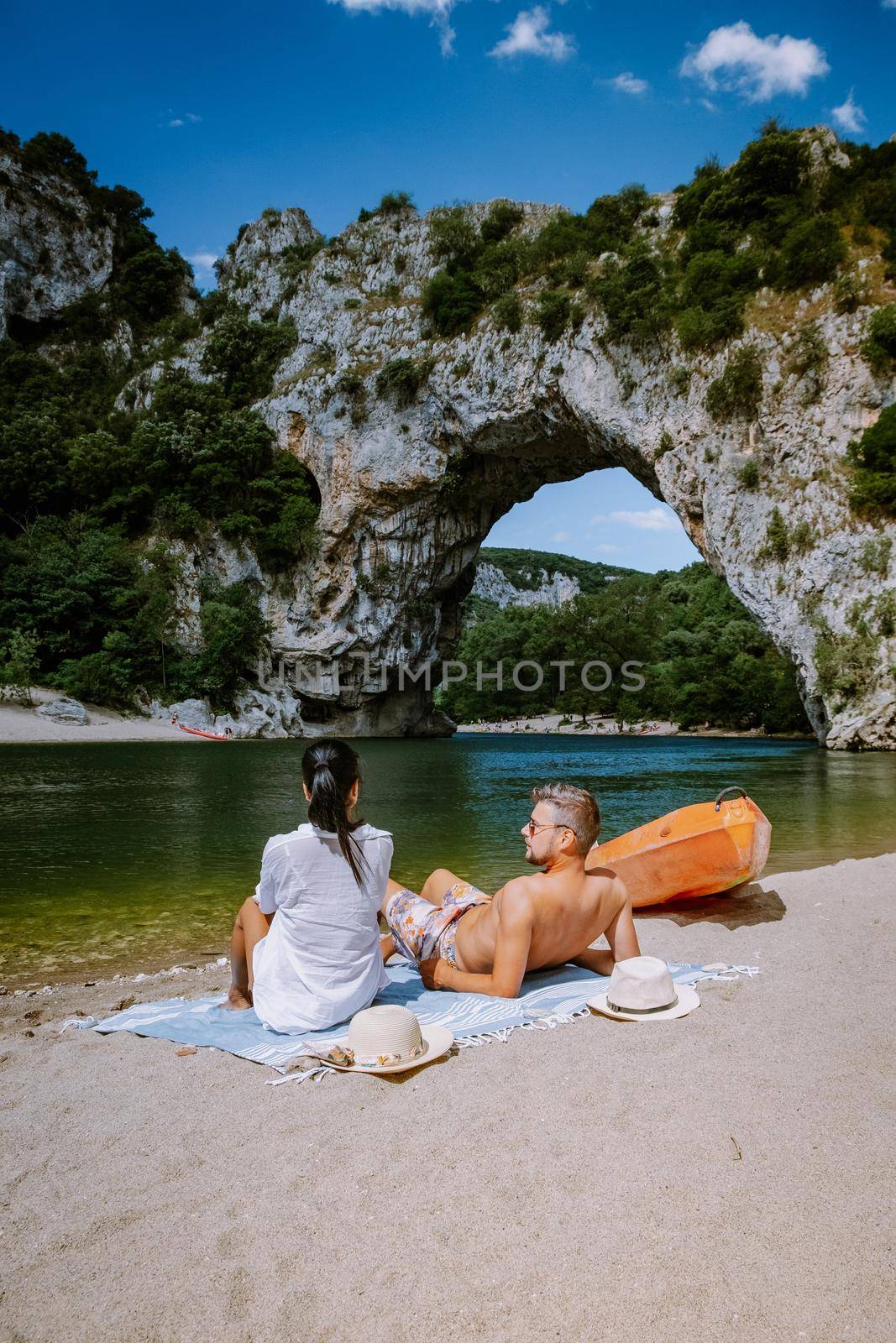 couple on the beach by the river in the Ardeche France Pont d Arc, Ardeche France,view of Narural arch in Vallon Pont D'arc in Ardeche canyon in France by fokkebok