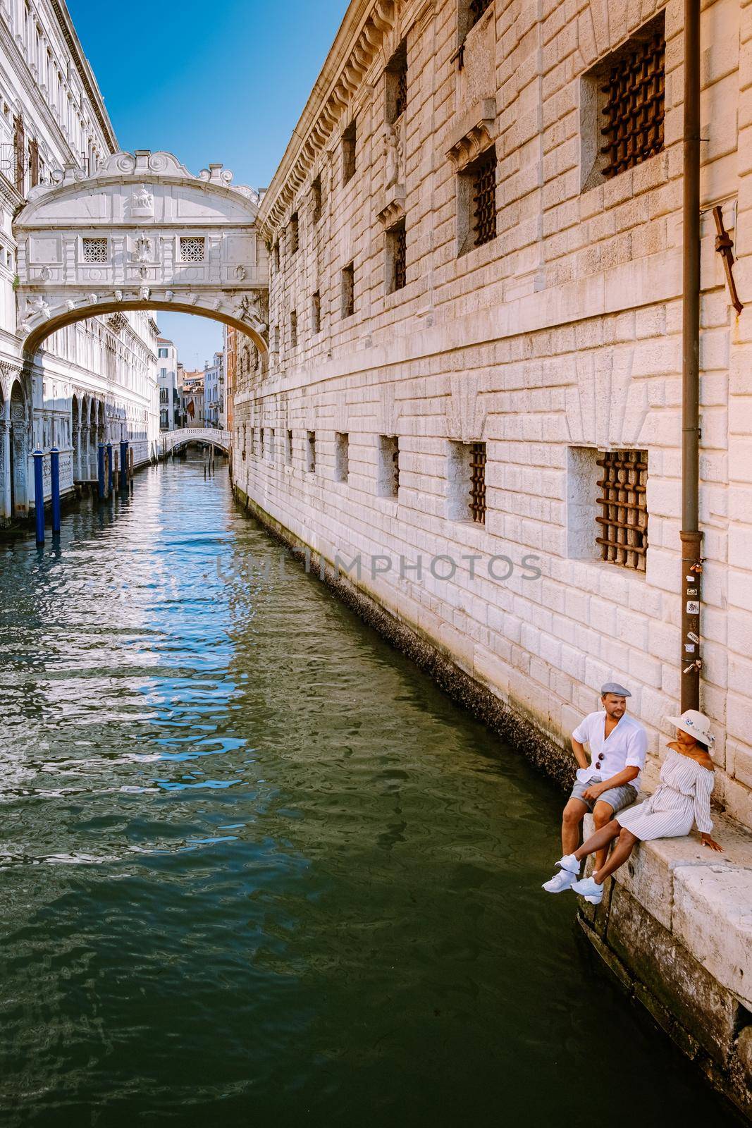 couple on a city trip in Venice, Loving couple on vacation in Venice, Italy Millennials sitting on a canal with gondolas. Europe