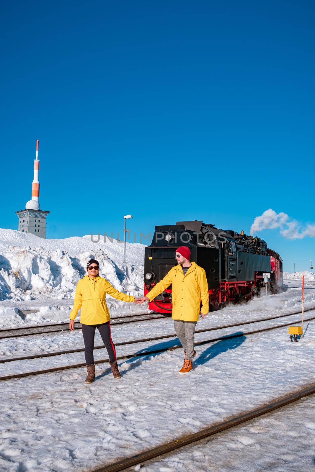 couple men and woman hiking in the Harz national park Germany, Steam train on the way to Brocken through the winter landscape, Famous steam train through the winter mountain. Brocken, Harz Germany