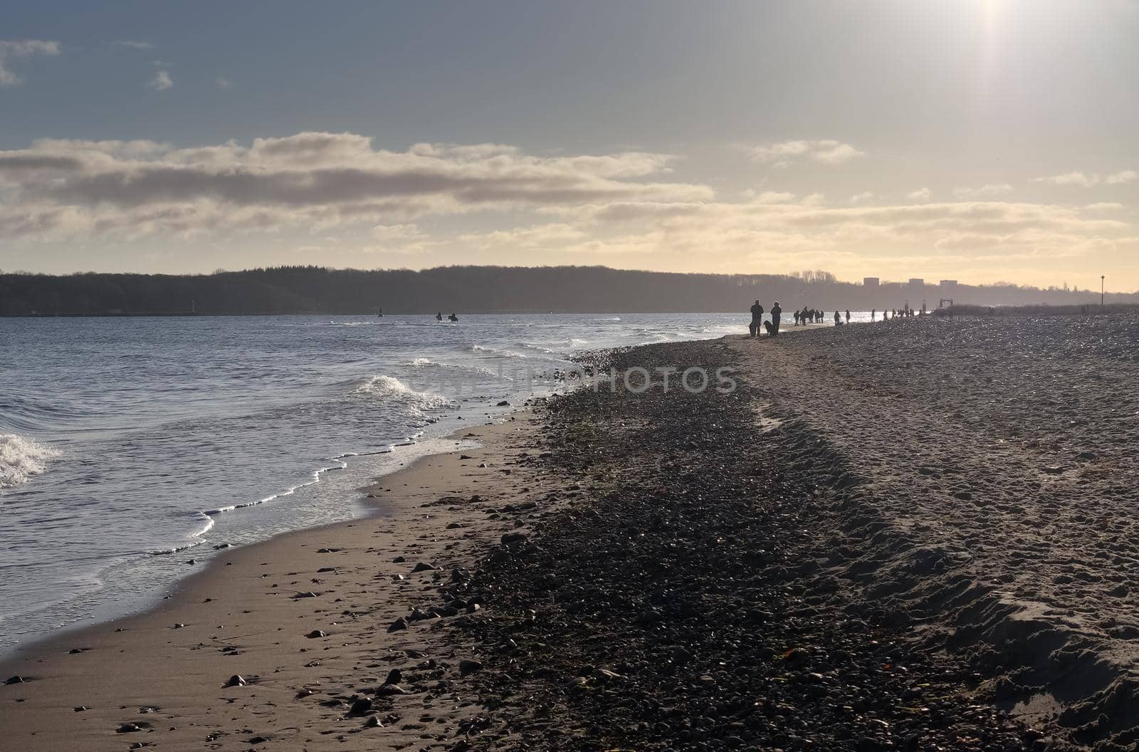 Silhouettes of people talking a walk on a sunny baltic sea beach in Germany