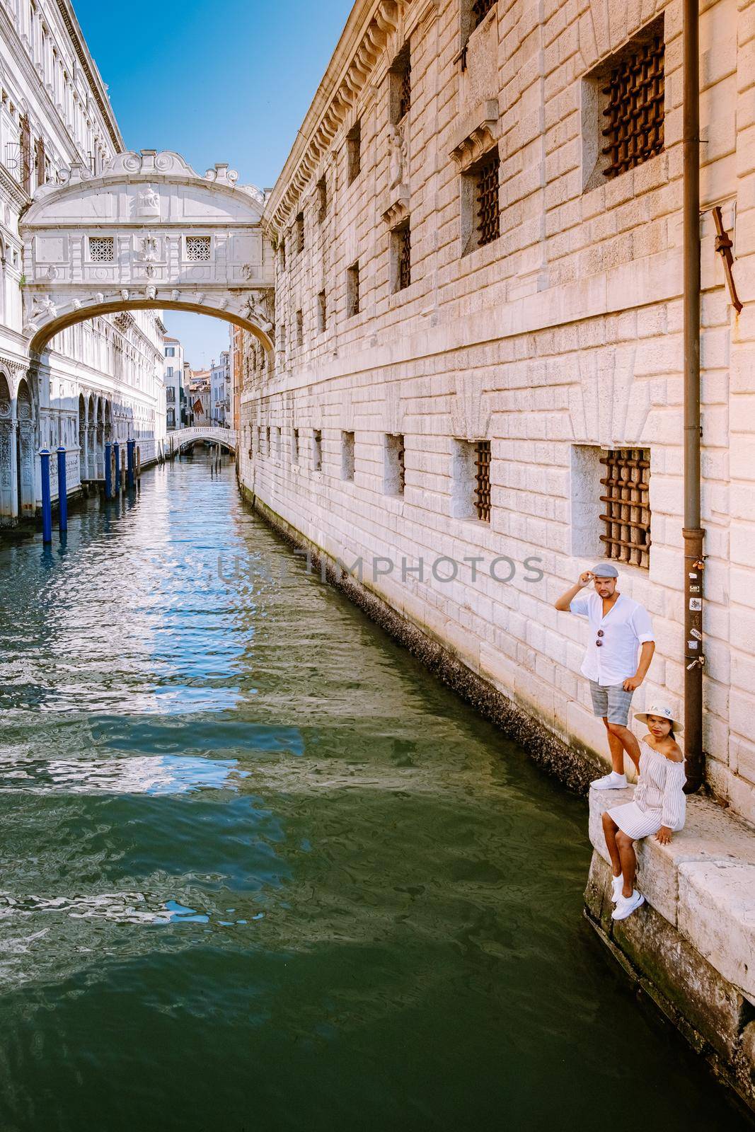 couple on a city trip in Venice, Loving couple on vacation in Venice, Italy Millennials sitting on a canal with gondolas by fokkebok