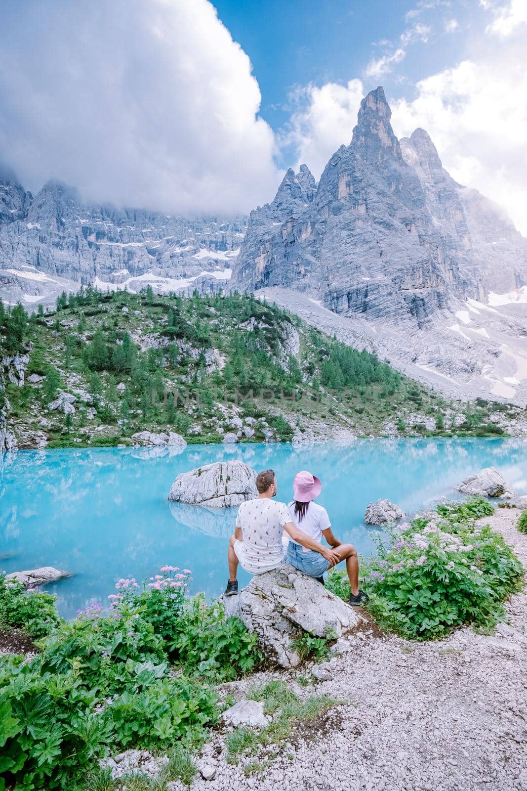 Couple visit the blue green lake in the Italian Dolomites,Beautiful Lake Sorapis Lago di Sorapis in Dolomites, popular travel destination in Italy by fokkebok