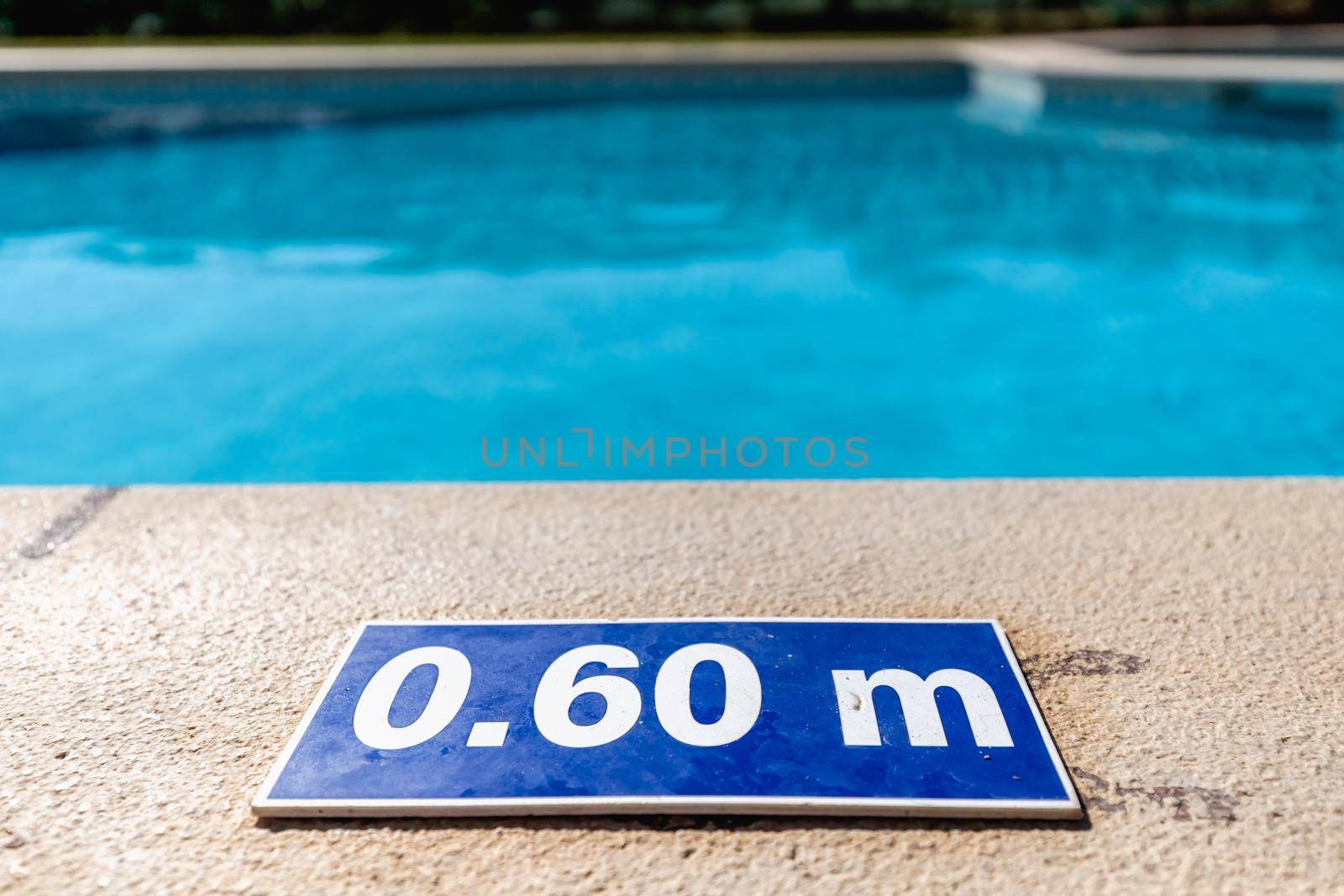 blue plastic plate at the edge of a swimming pool indicating a depth of 0.60 meters