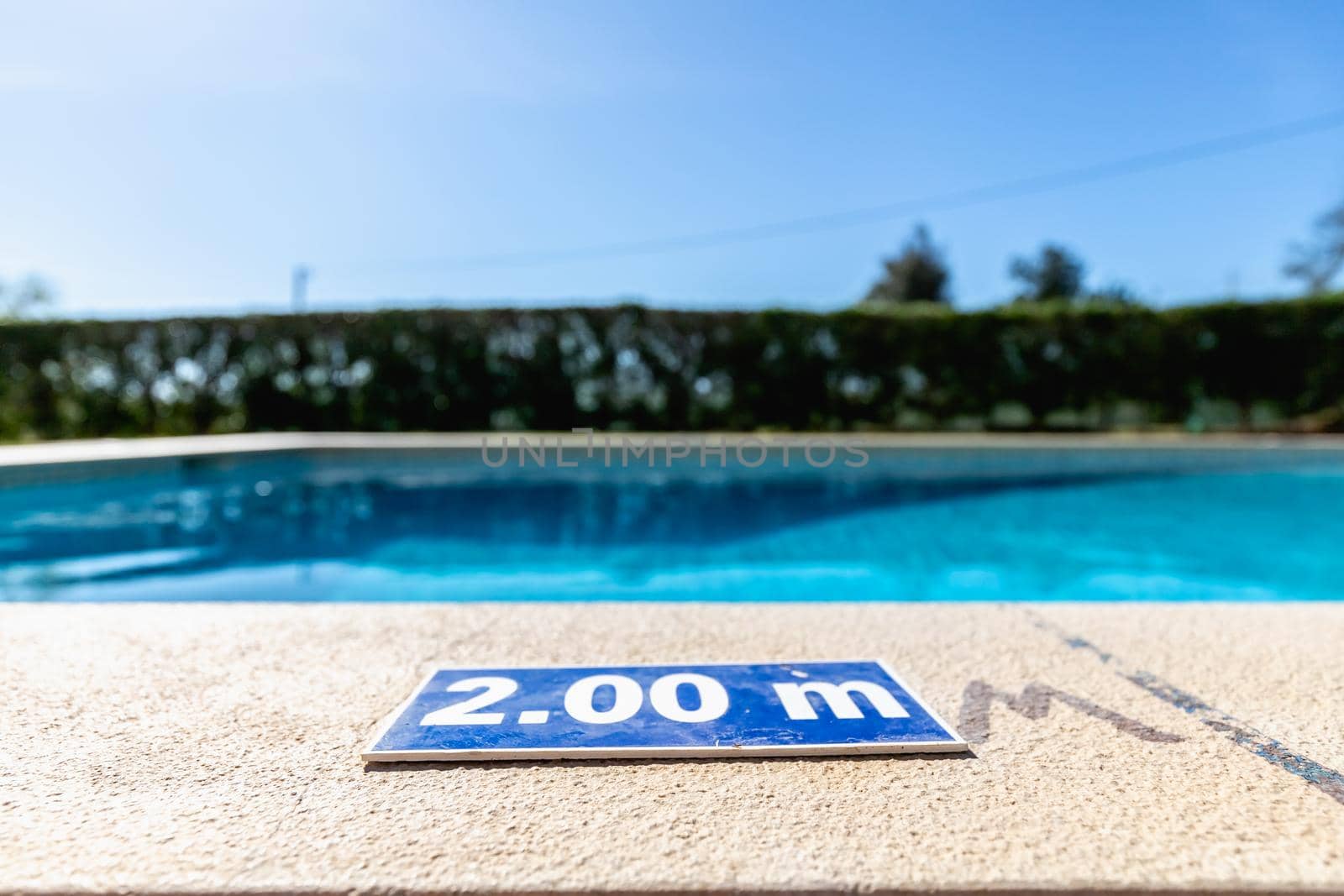 blue plastic plate at the edge of a swimming pool indicating a depth of 2.00 meters