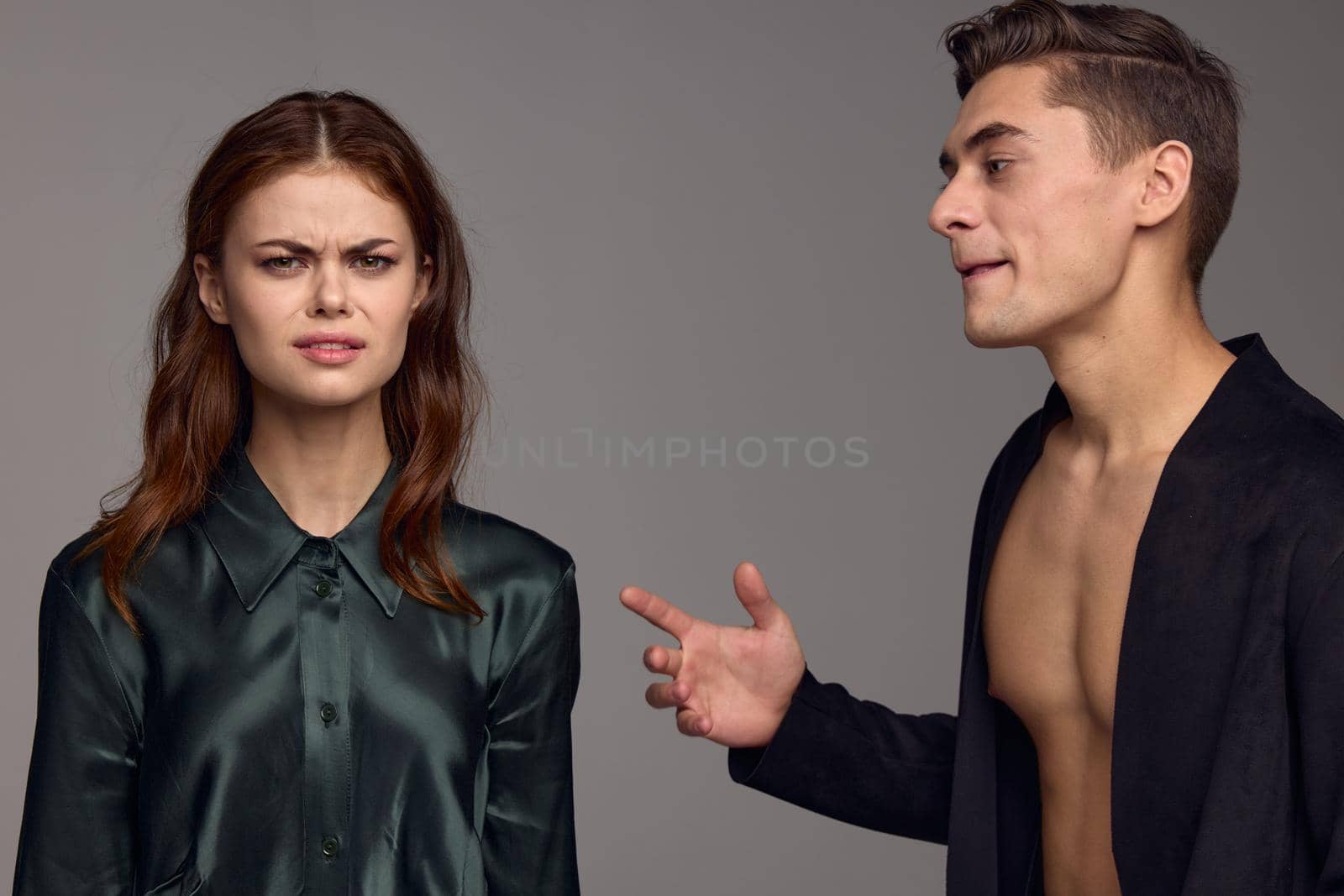 A nice man in a black jacket on a naked torso and a nice woman on a gray background. High quality photo