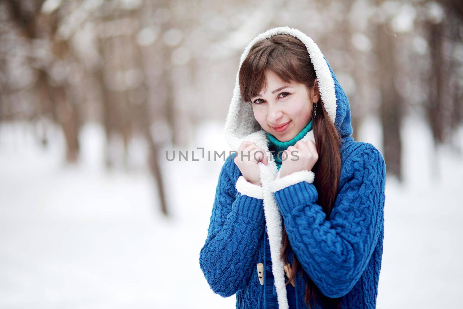 Winter portrait of a lovely girl in a blue sweater on the background of a snowy forest by selinsmo