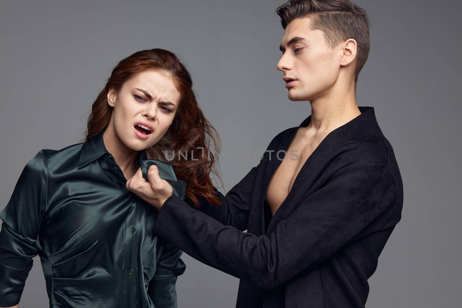 Man in a jacket mistreats a woman on a gray background domestic violence. High quality photo