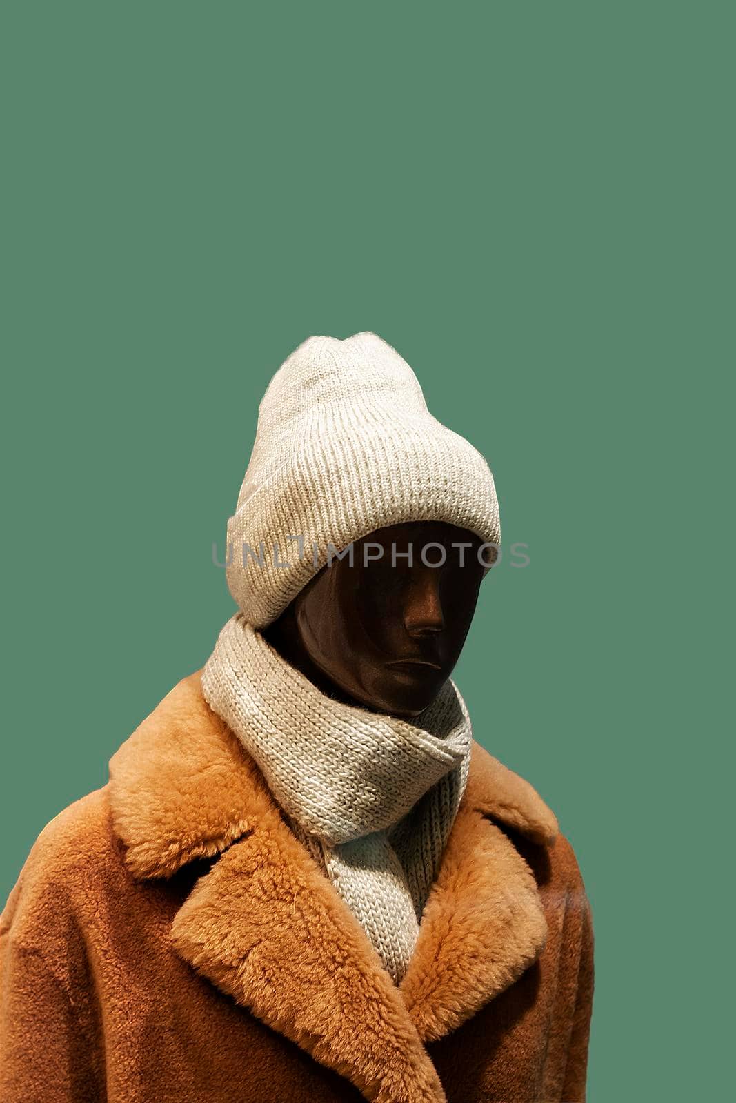 Dark-skinned female mannequin in hat and coat. On a gray background. Front view from the side. by Essffes