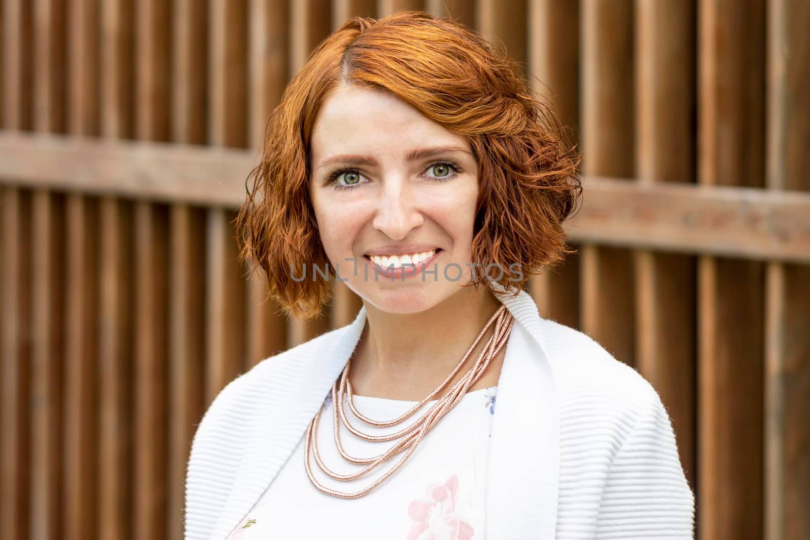 Woman with white teeth is smiling. Against background of brown textured wooden wall. by Essffes