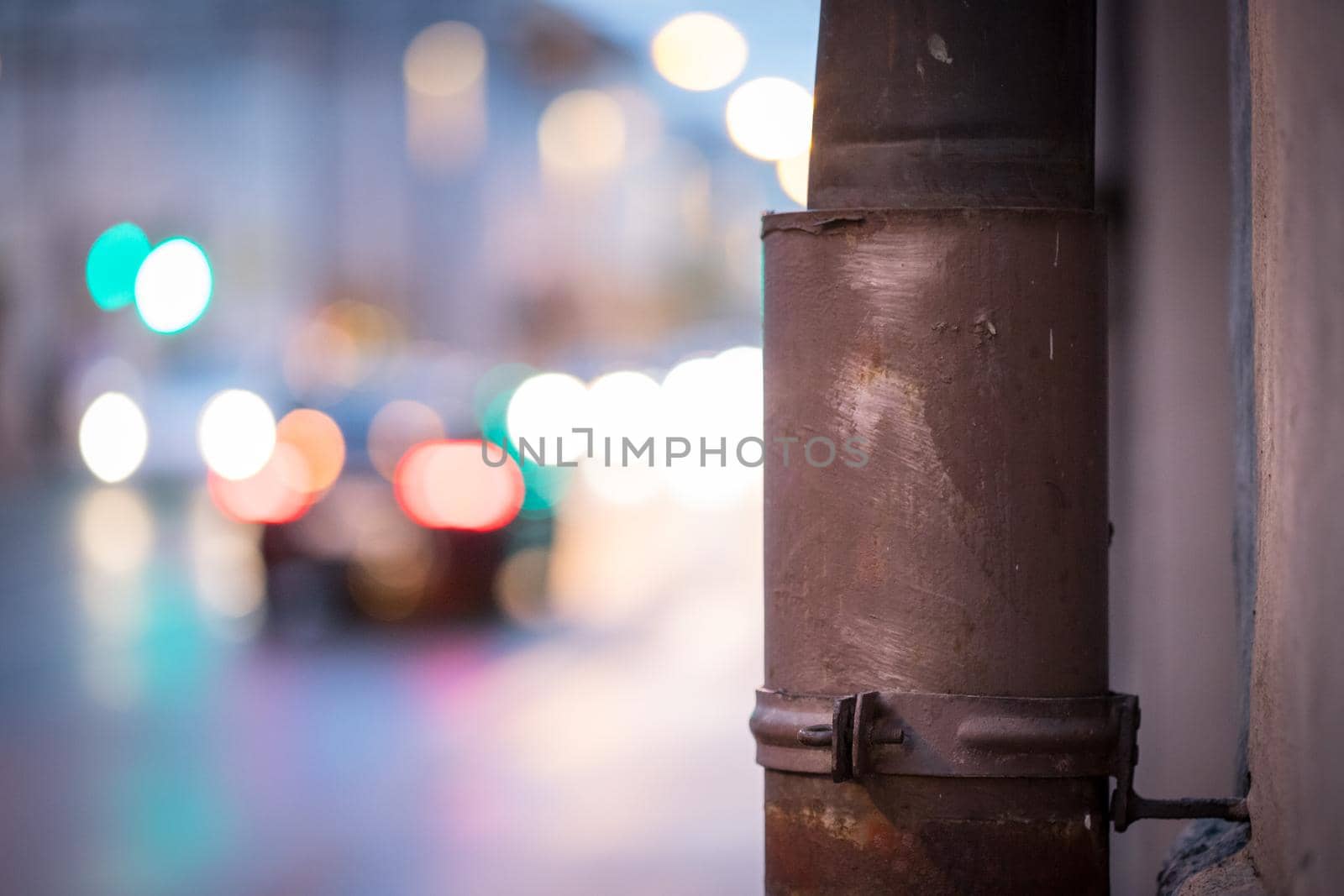 Closeup of rain drain, urban city lights in the blurry background