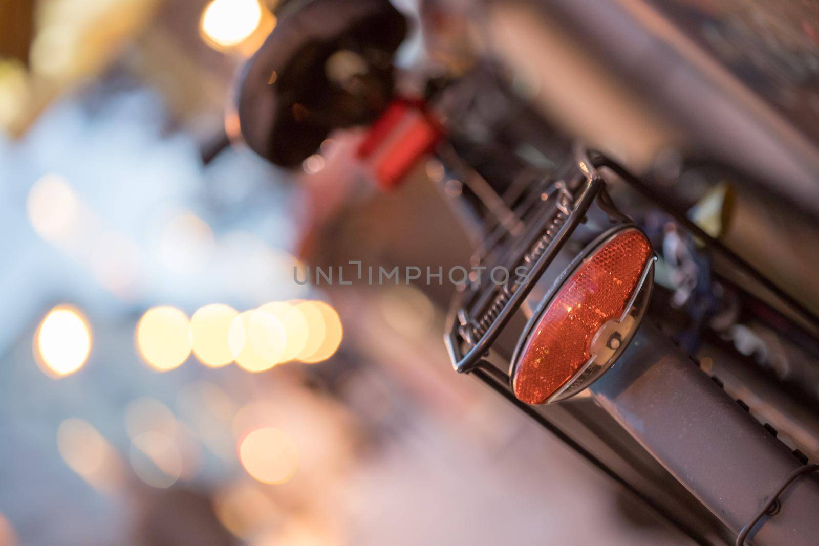 Rear picture of a city bike, blurry background with city lights, evening