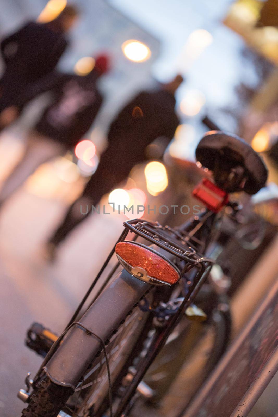 Rear picture of a city bike, blurry background with city lights, evening