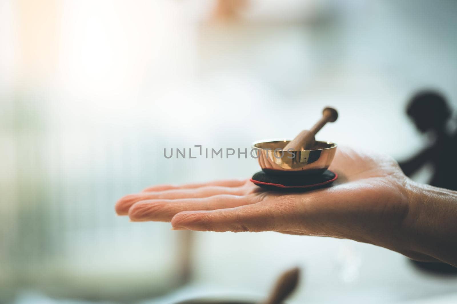 Small singing bowl holding in hand, blurry background