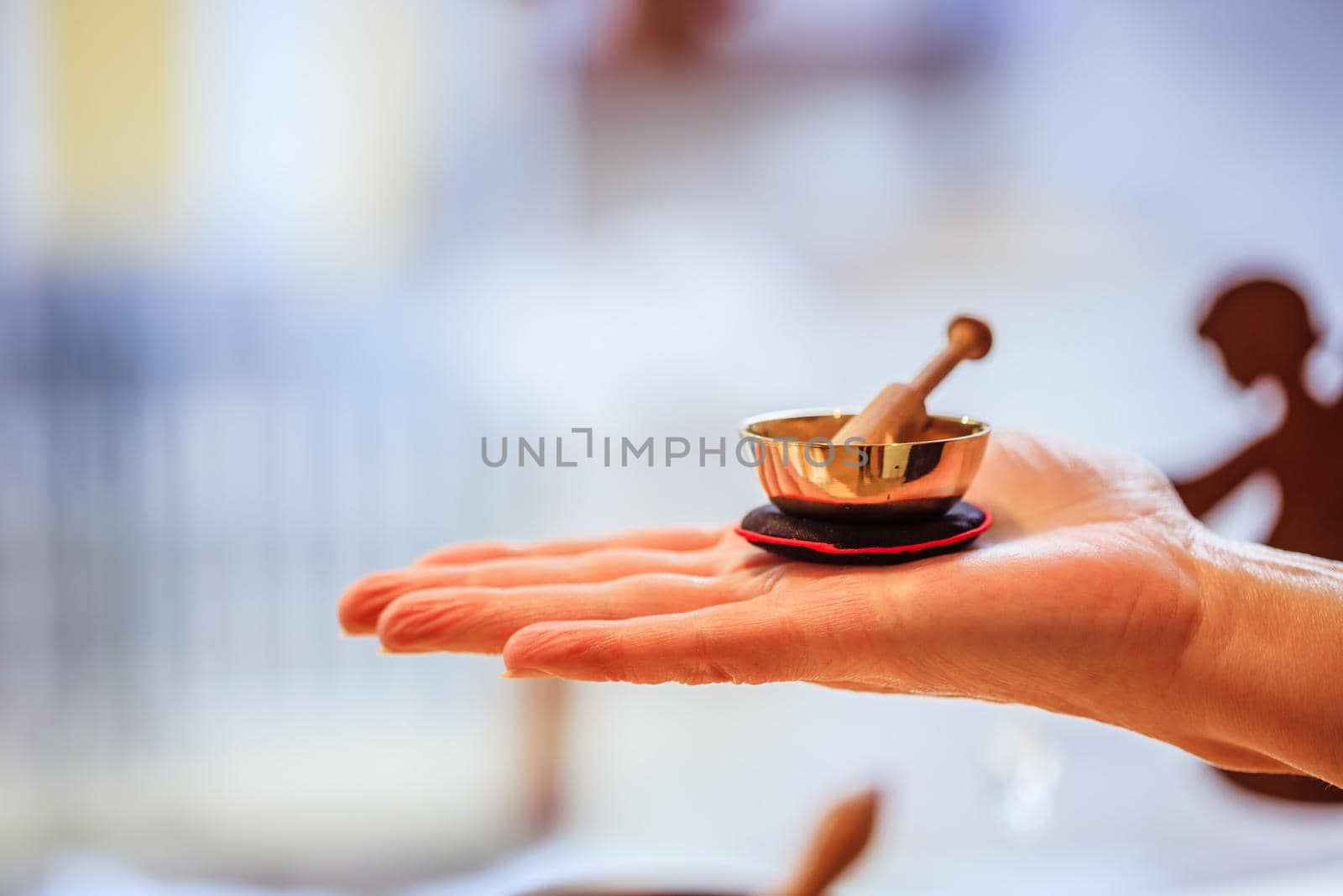 Small singing bowl holding in hand, blurry background