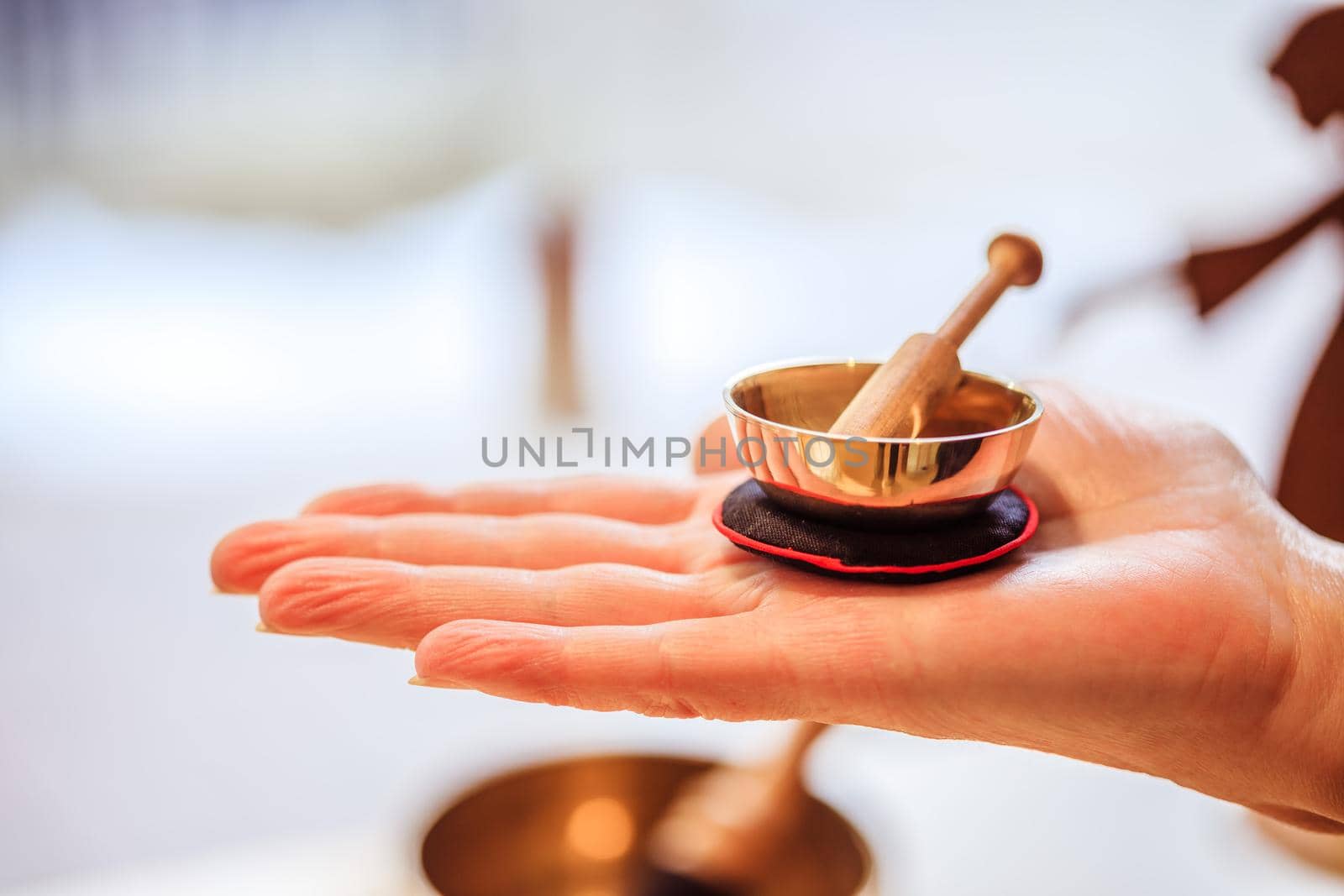 Small singing bowl holding in hand, blurry background