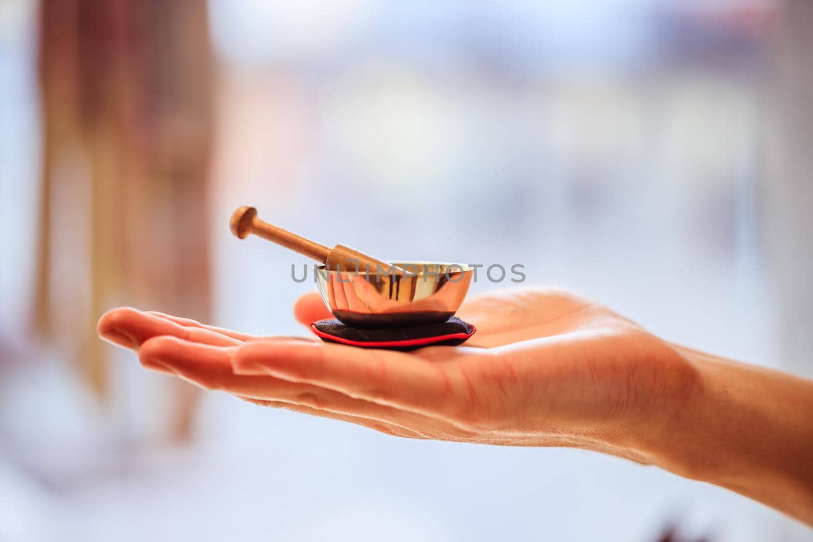 Small singing bowl holding in hand, blurry background