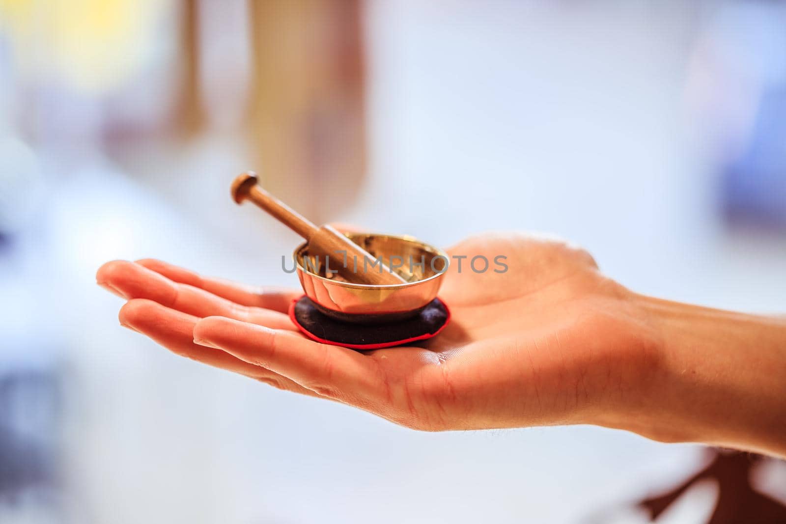 Small singing bowl holding in hand, blurry background
