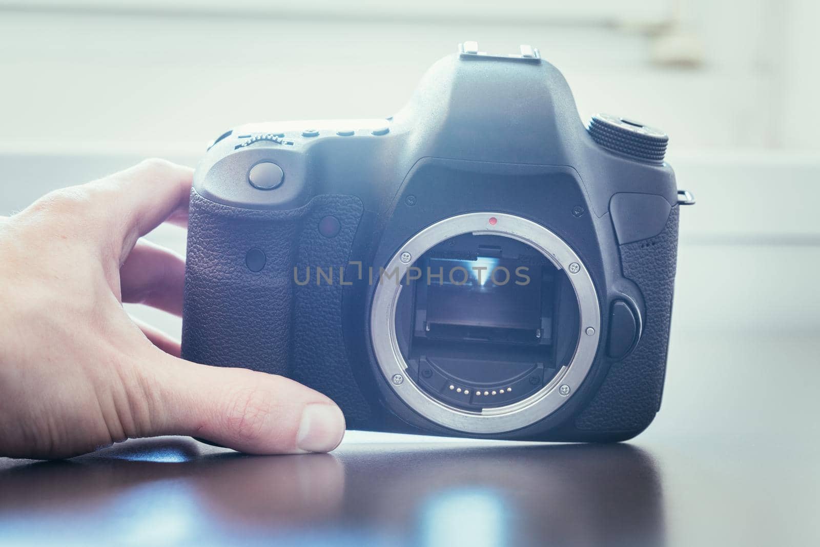 Hands of a photographer are touching a professional reflex camera, open sensor